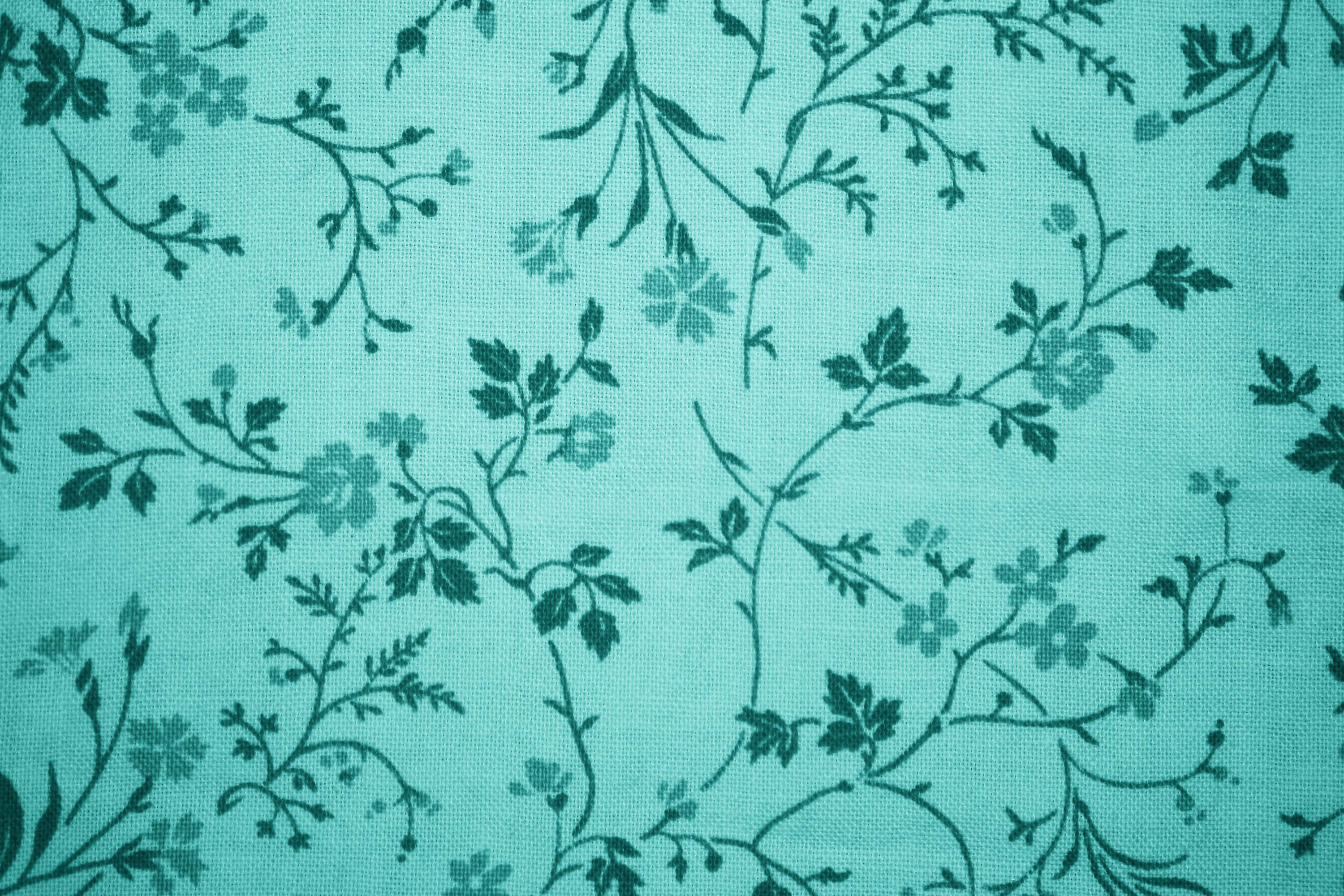 Teal Blue 桌布 壁紙 — 深綠色花卉藤蔓和花朵重複圖案的青綠色布料特寫。