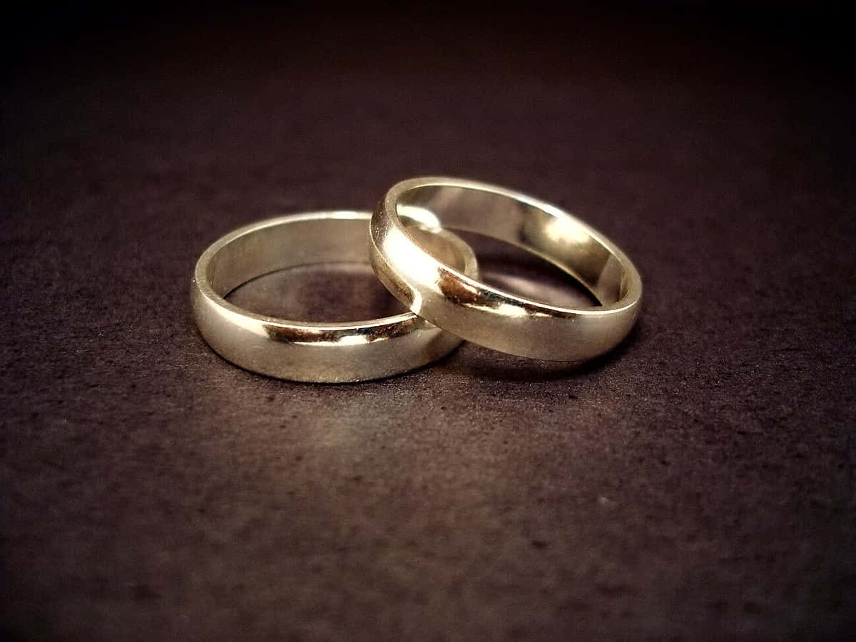 兩枚銀色結婚戒指在深色紋理表面上交織。