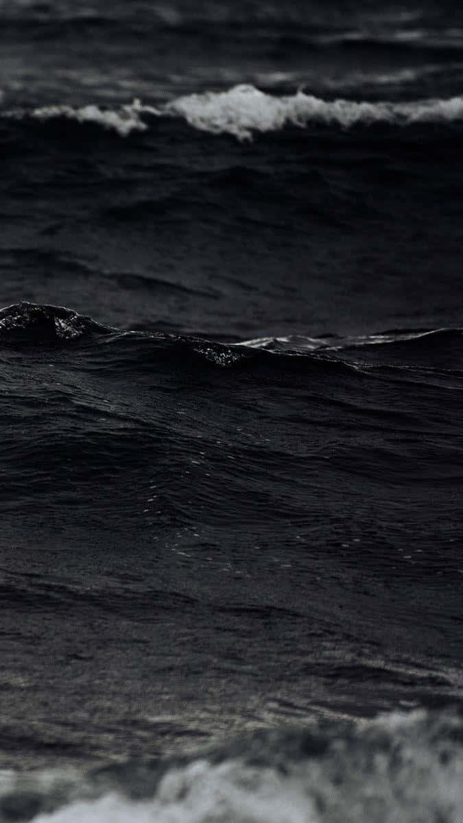 Black And White Ocean 桌布 壁紙 — 深色海浪帶著白色泡沫，在昏暗光線下拍打著陰鬱的單色海洋。