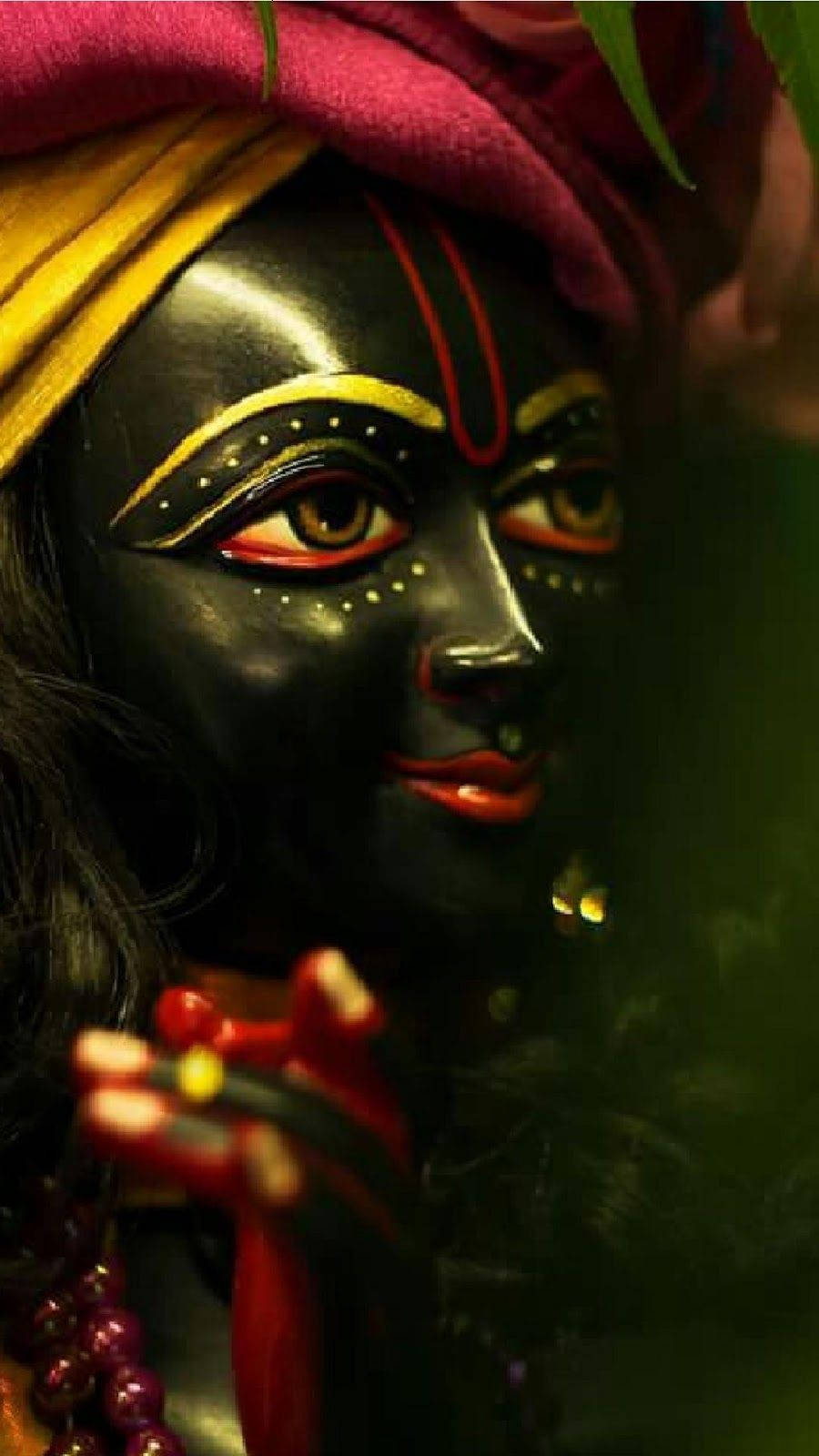krishna phone 桌布 壁紙 — 深色皮膚神祇的特寫，帶有鮮豔的黃色和紅色面部標記以及色彩繽紛的頭巾。