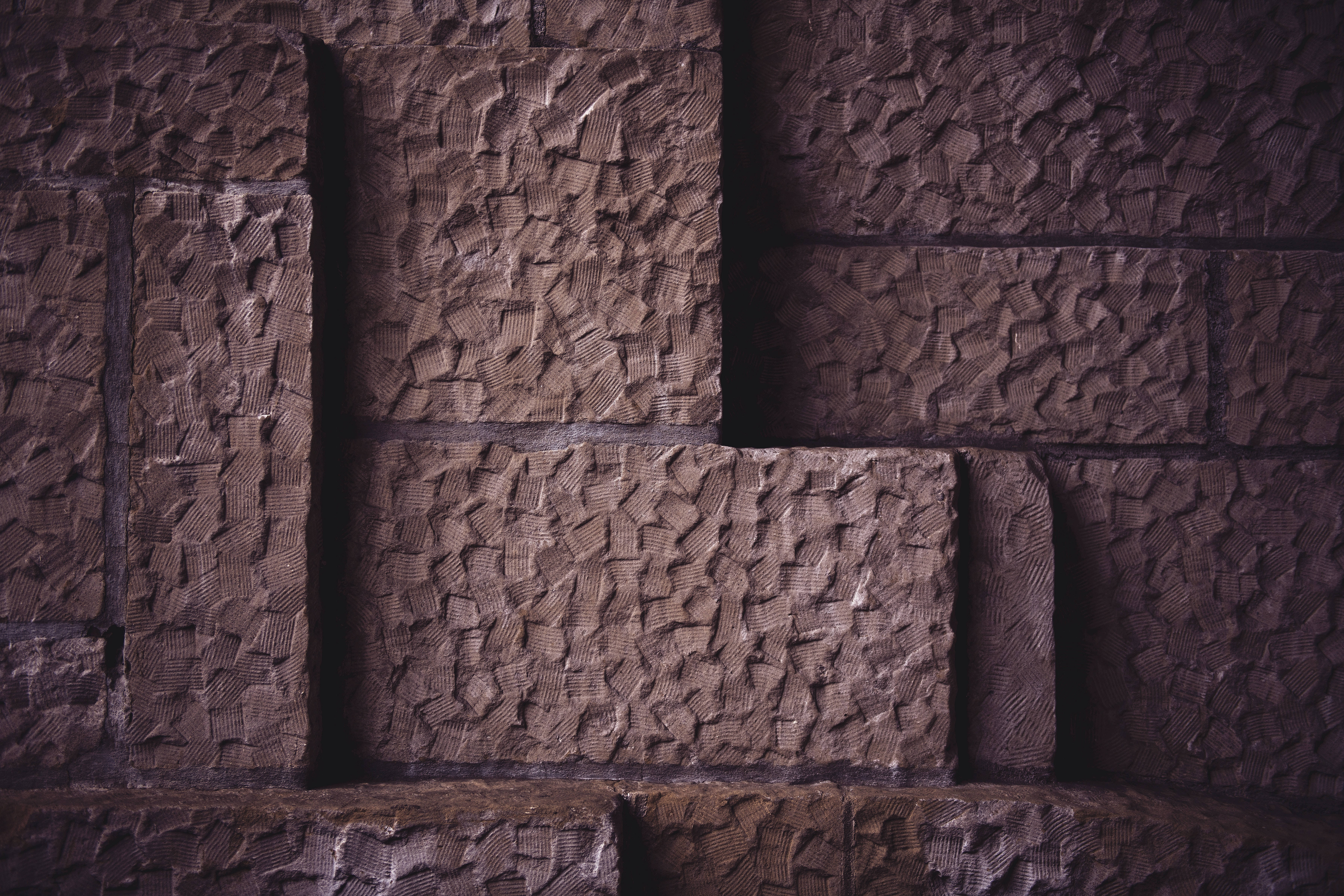 Brick 桌布 壁紙 — 深色紋理石塊的特寫，以粗糙的幾何圖案排列，帶有深邃陰影。