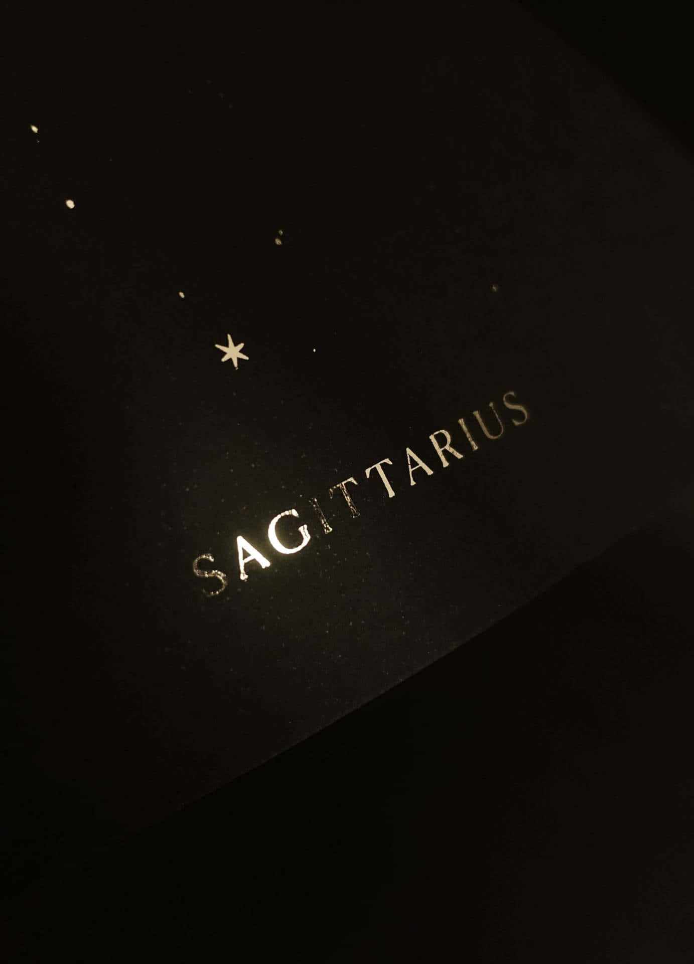 人馬座 桌布 壁紙 — 深色紋理表面上，以金箔呈現「Sagittarius」字樣，上方散落著金色星星。
