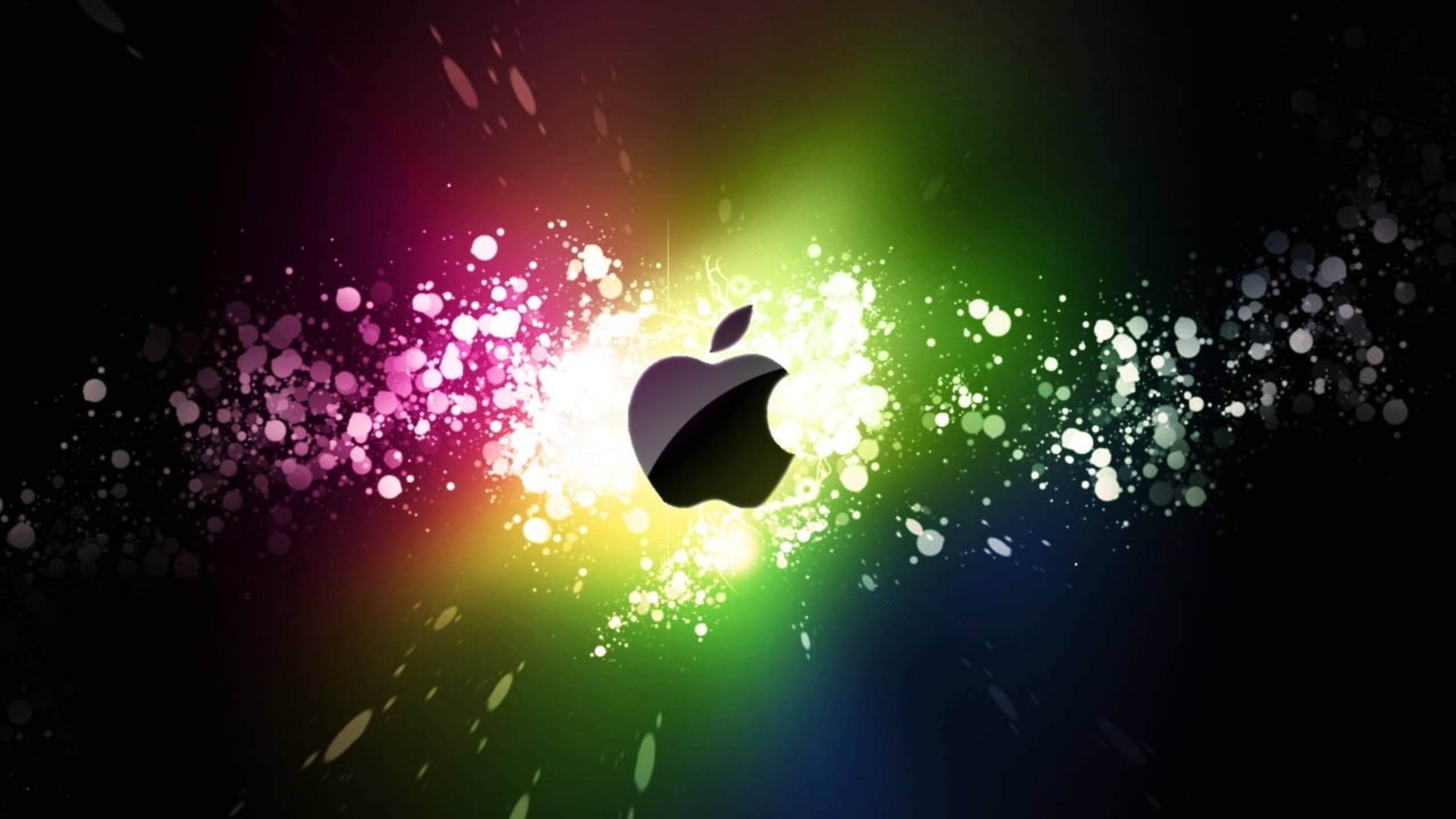 深色背景上的炫麗光譜色彩 壁紙 — 發光的Apple標誌在黑暗背景上散發出鮮豔的彩虹粒子。