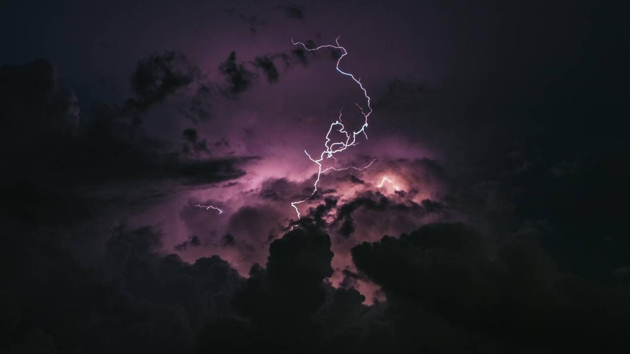 一道強烈的閃電照亮了暴風雨的紫色夜空。