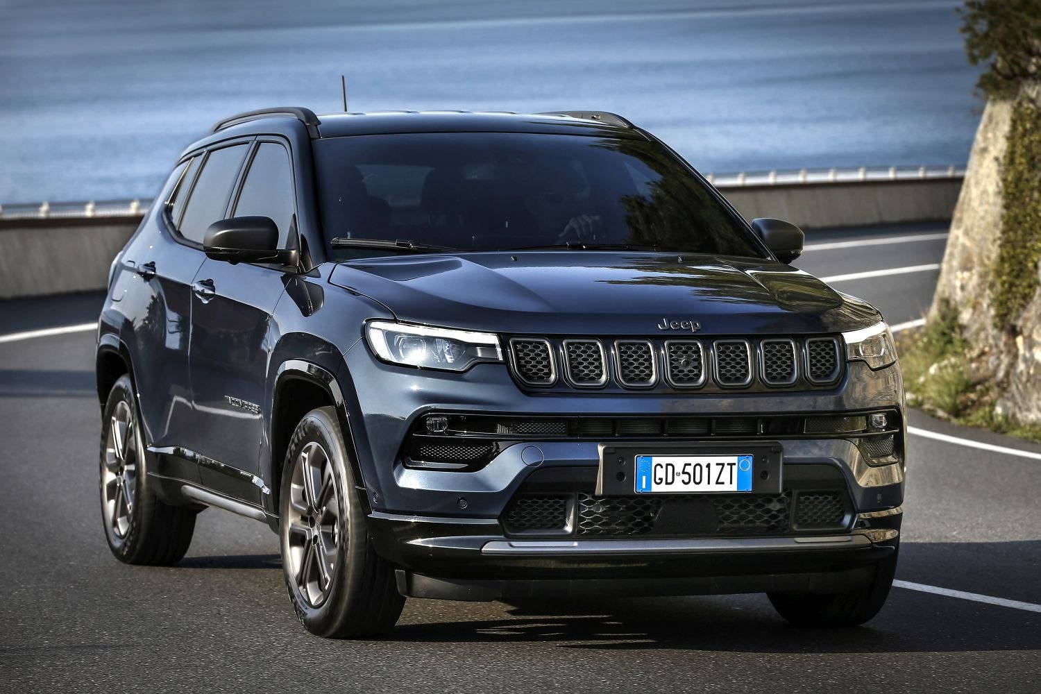 深藍色Jeep Compass在海岸道路上行駛。