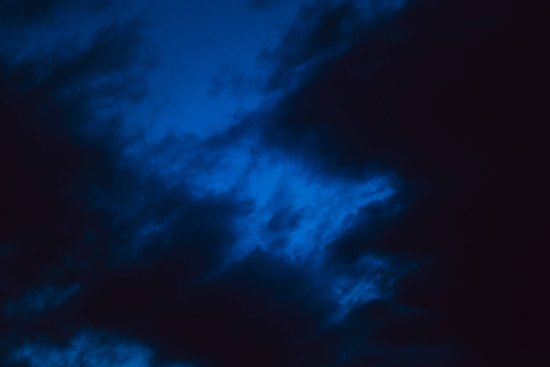 黑暗的雲朵在夜空中被深藍色照亮。