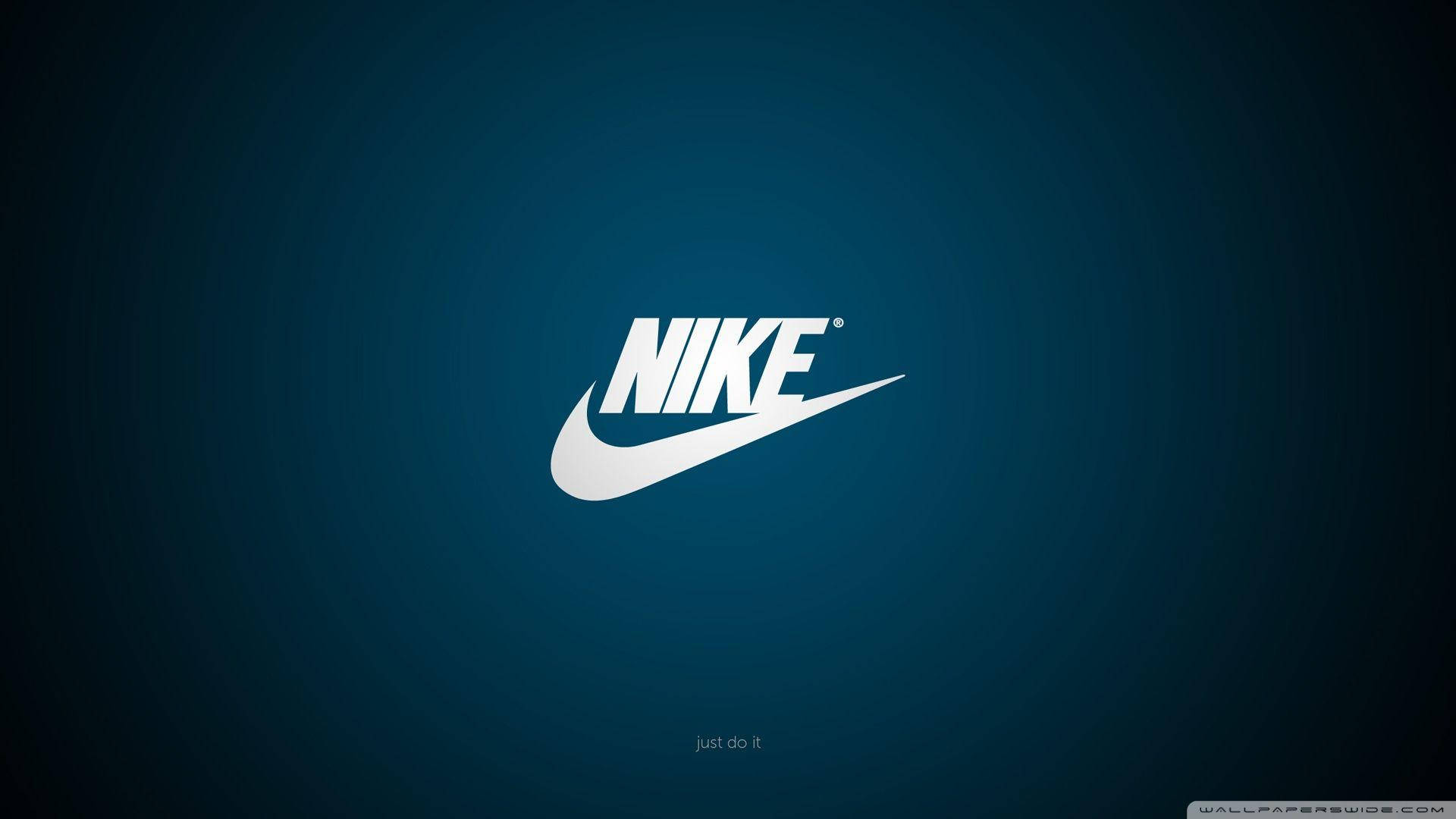 深藍漸層背景酷炫耐克標誌 壁紙 — 白色Nike swoosh標誌居中於漸變藍色背景上，帶有微妙的徑向光效。