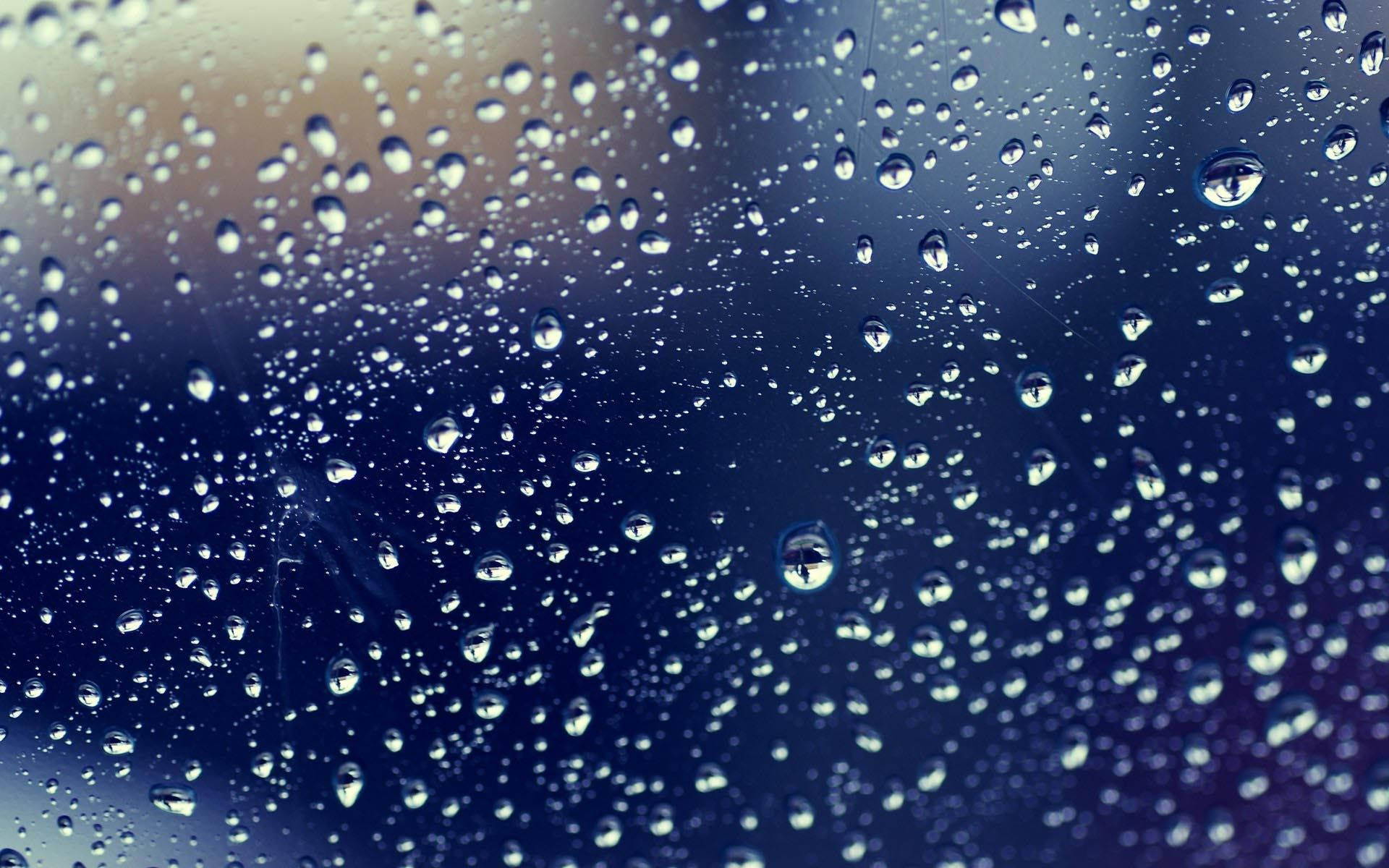 窗戶上的雨滴，背景模糊的藍色和黃色。