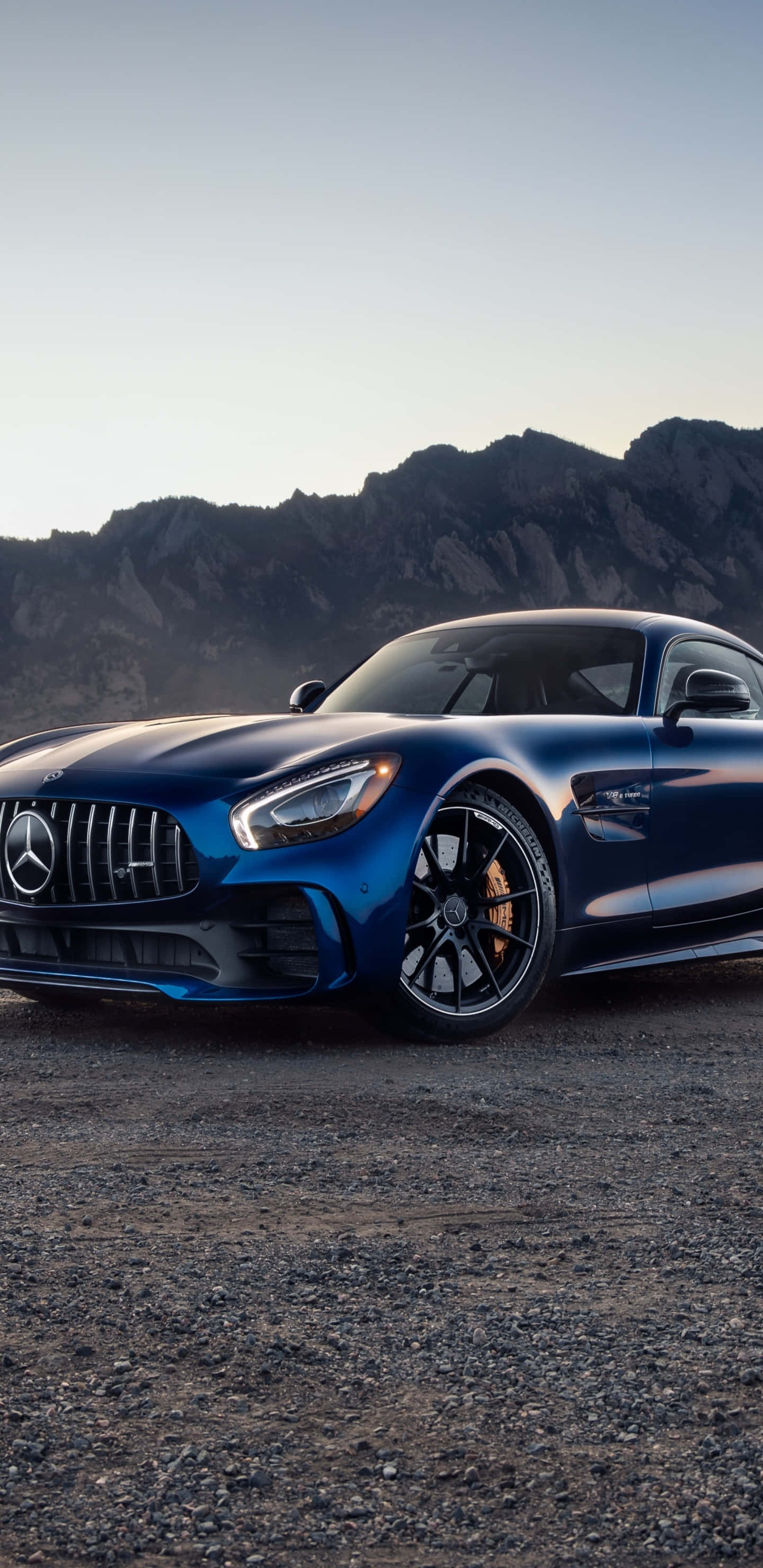 深藍色梅賽德斯-奔馳 Pixel 3XL AMG GT-R 背景 壁紙 — 一架時尚的藍色 Mercedes-AMG GT 跑車停在碎石上，背景是黃昏時崎嶇的山脈。