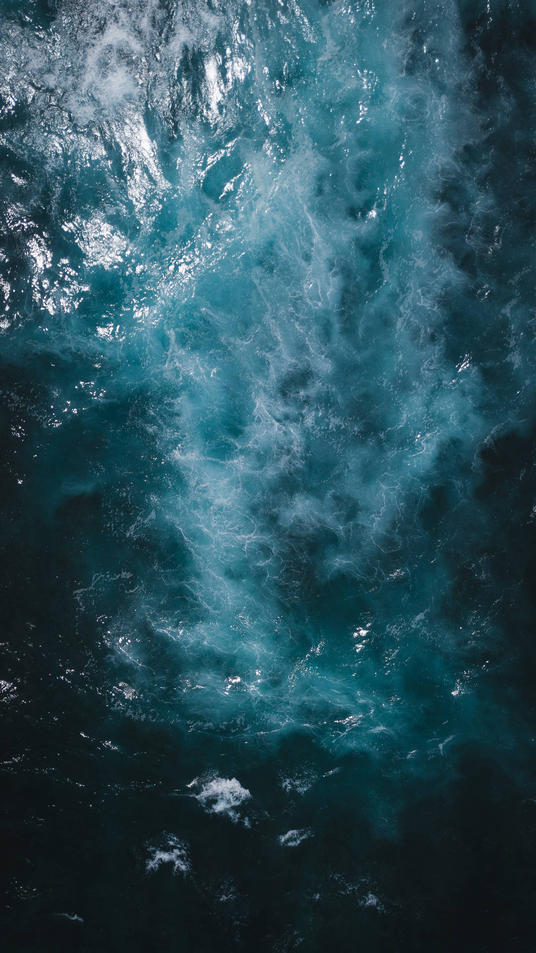 從上方看到的，在深藍色海水中撞擊的帶有白色泡沫的洶湧海浪。
