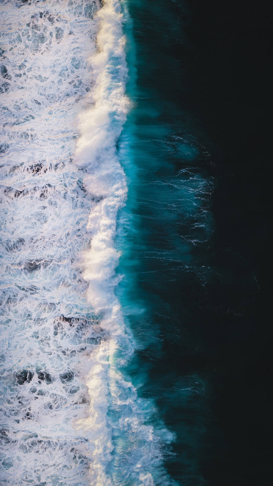 從高空拍攝海洋波浪在深藍色海水中破碎成白色泡沫。