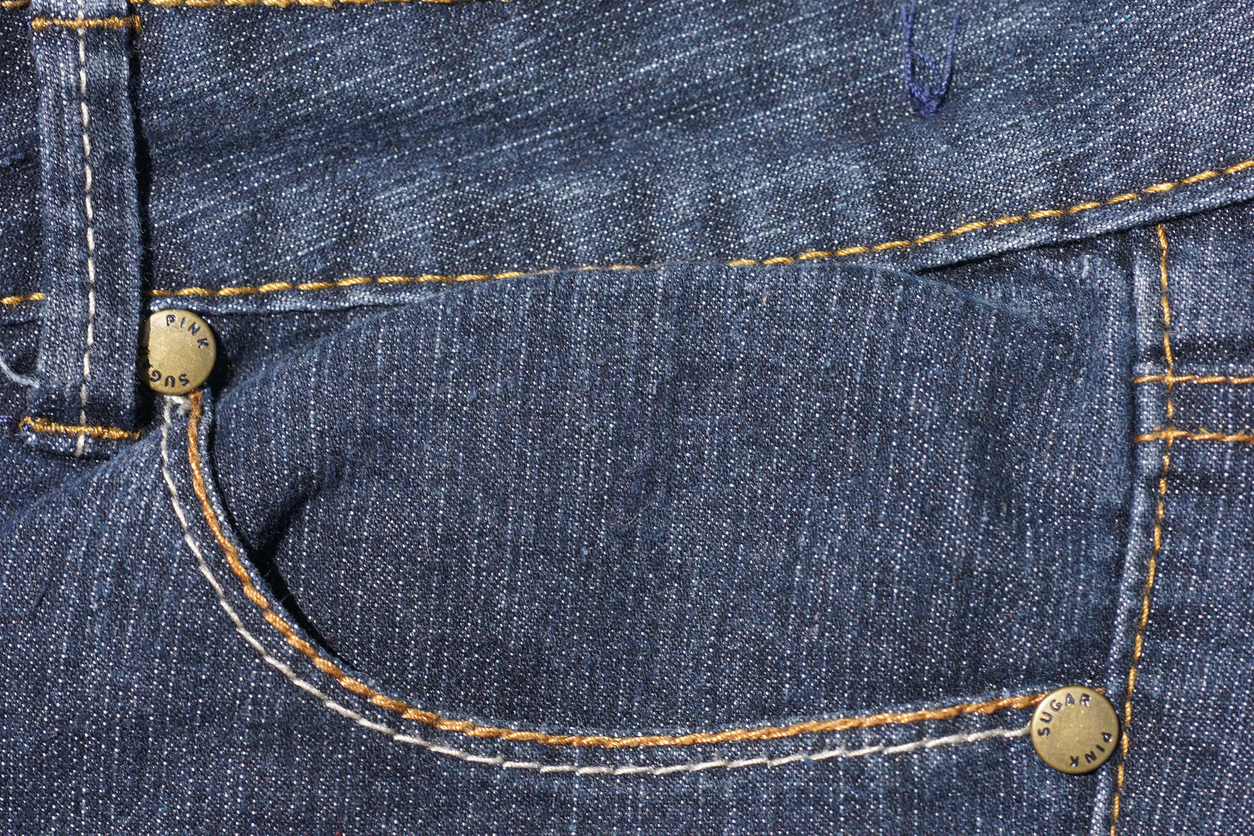 Denim Blue 桌布 壁紙 — 深藍色牛仔褲口袋特寫，帶有對比鮮明的橙色和白色縫線及品牌黃銅鈕扣。
