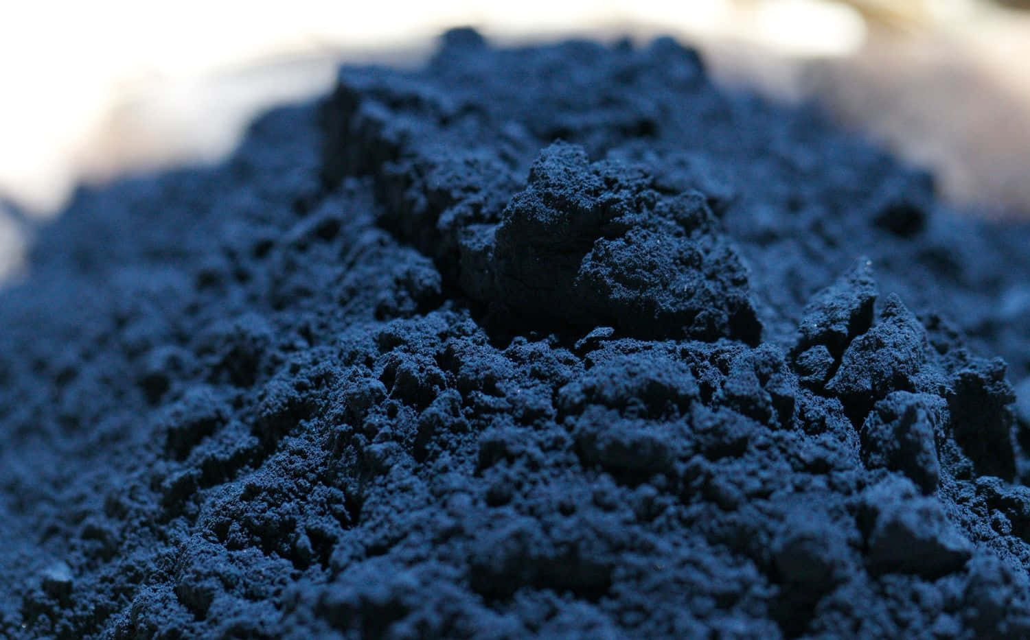 Indigo Blue 桌布 壁紙 — 深藍色粉末的特寫，帶有紋理塊狀和柔和背景模糊。