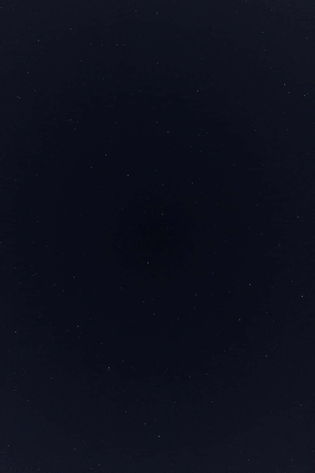 Minimalist Phone 桌布 壁紙 — 深邃的海軍藍夜空點綴著微弱的星星，營造出寧靜的宇宙廣闊景象。