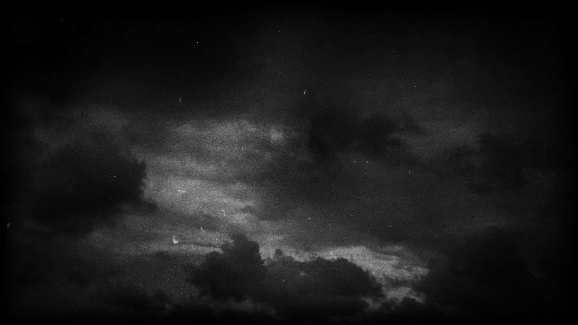 黑暗多雲的夜空，可見星星和顆粒狀紋理。