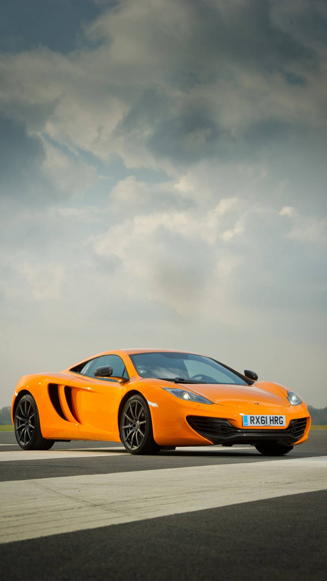 橙色McLaren跑車在賽道上，天空烏雲密布