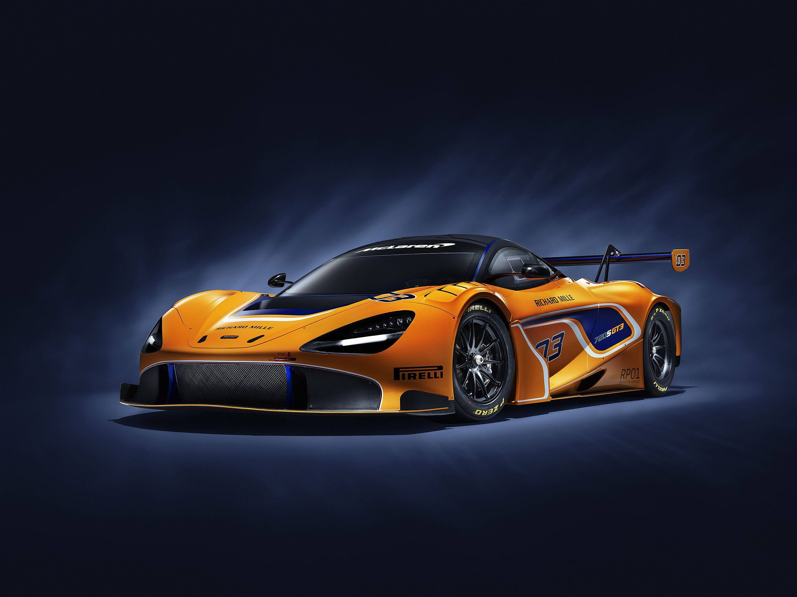 深黃色賽車競速 壁紙 — 一輛時尚的橙色McLaren賽車，帶有藍色點綴和號碼03，在戲劇性的攝影棚燈光下，在深色背景中閃耀。