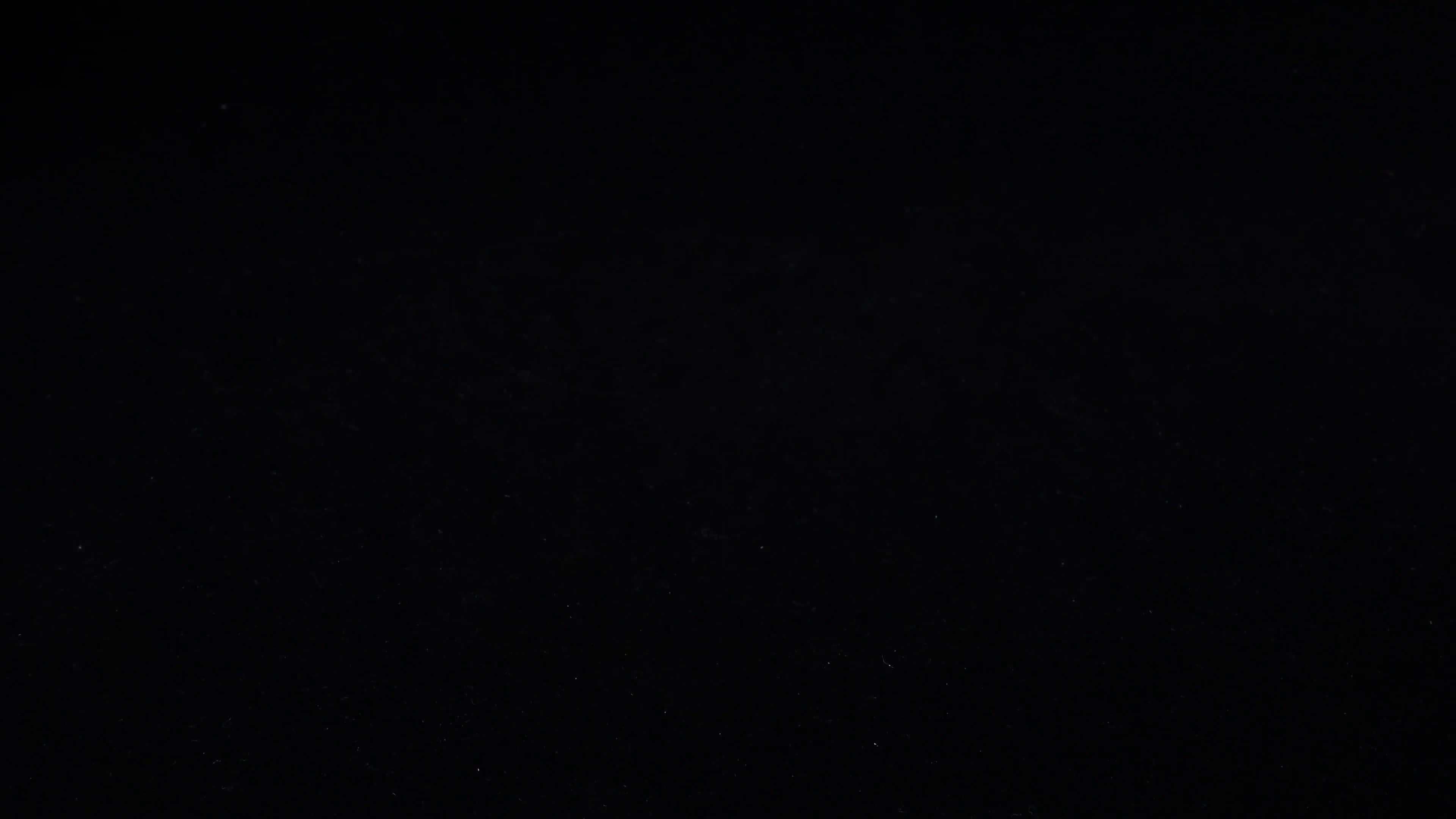 4K 黑色 桌布 壁紙 — 深黑色背景上散佈著微弱的白色斑點，類似遙遠的星星或塵埃粒子。