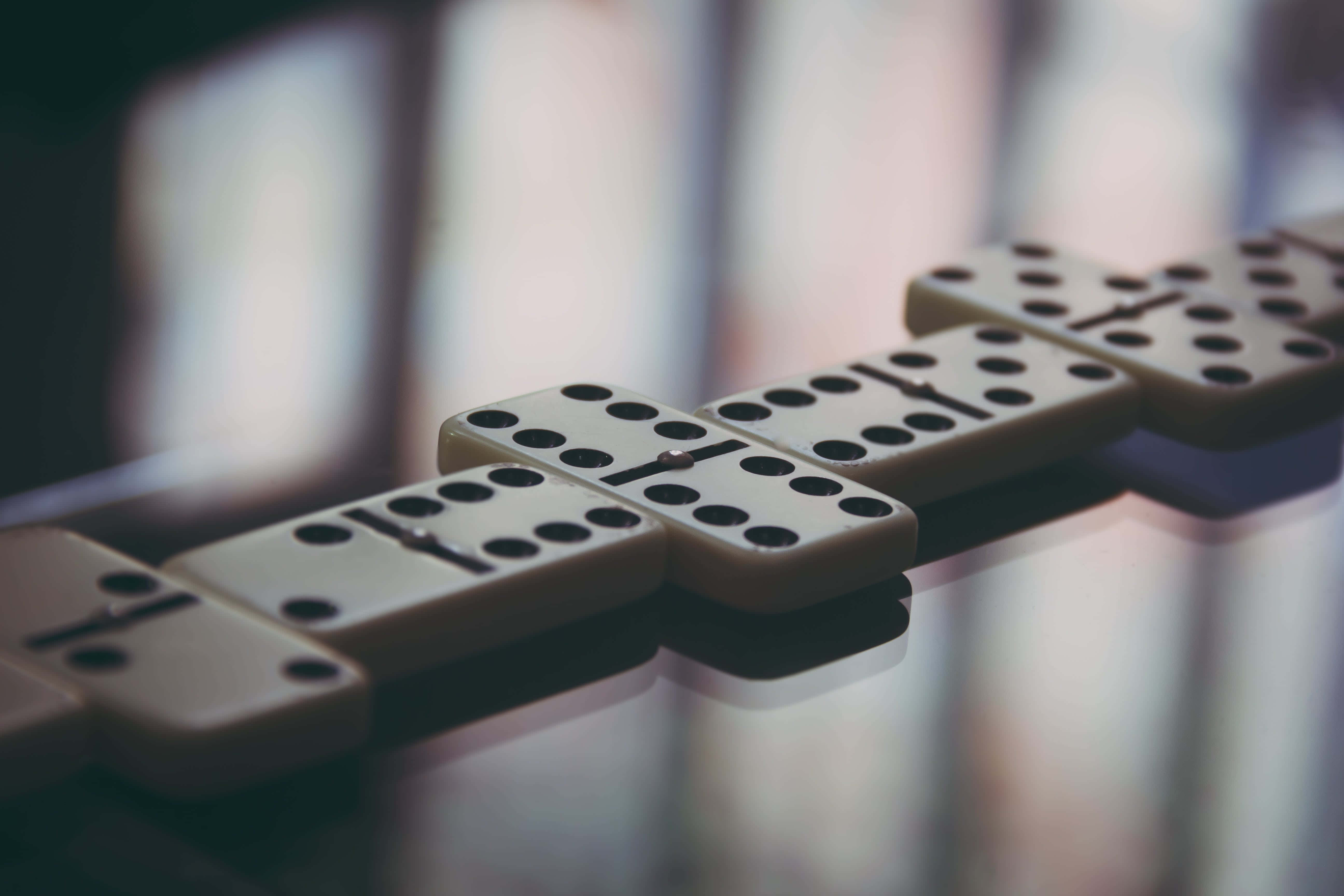 Domino 桌布 壁紙 — 淺景深捕捉到一排奶油色多米諾骨牌，上面有黑色圓點，排列在反光表面上。
