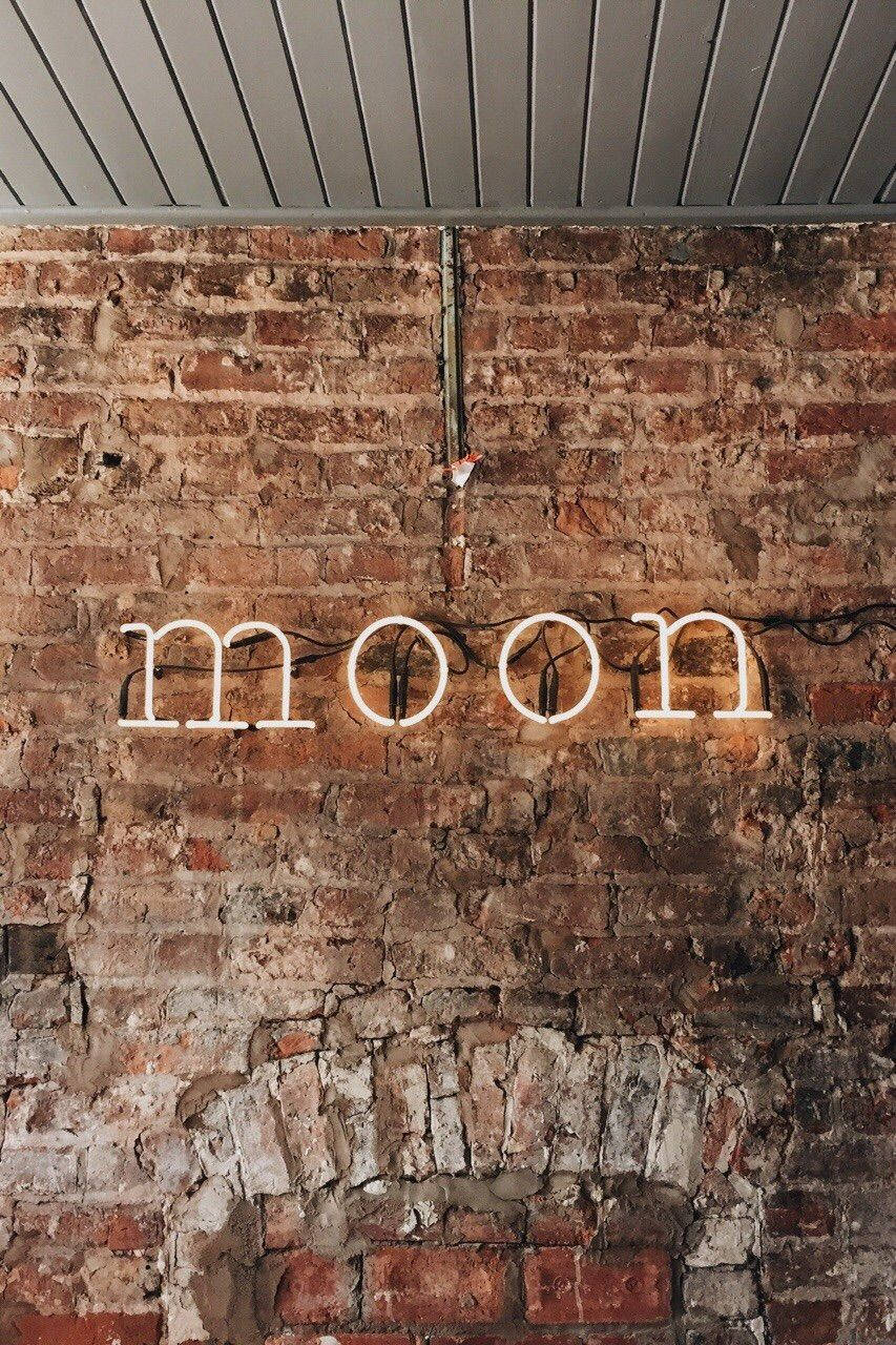 喺質樸磚牆上寫住moon嘅霓虹燈牌。