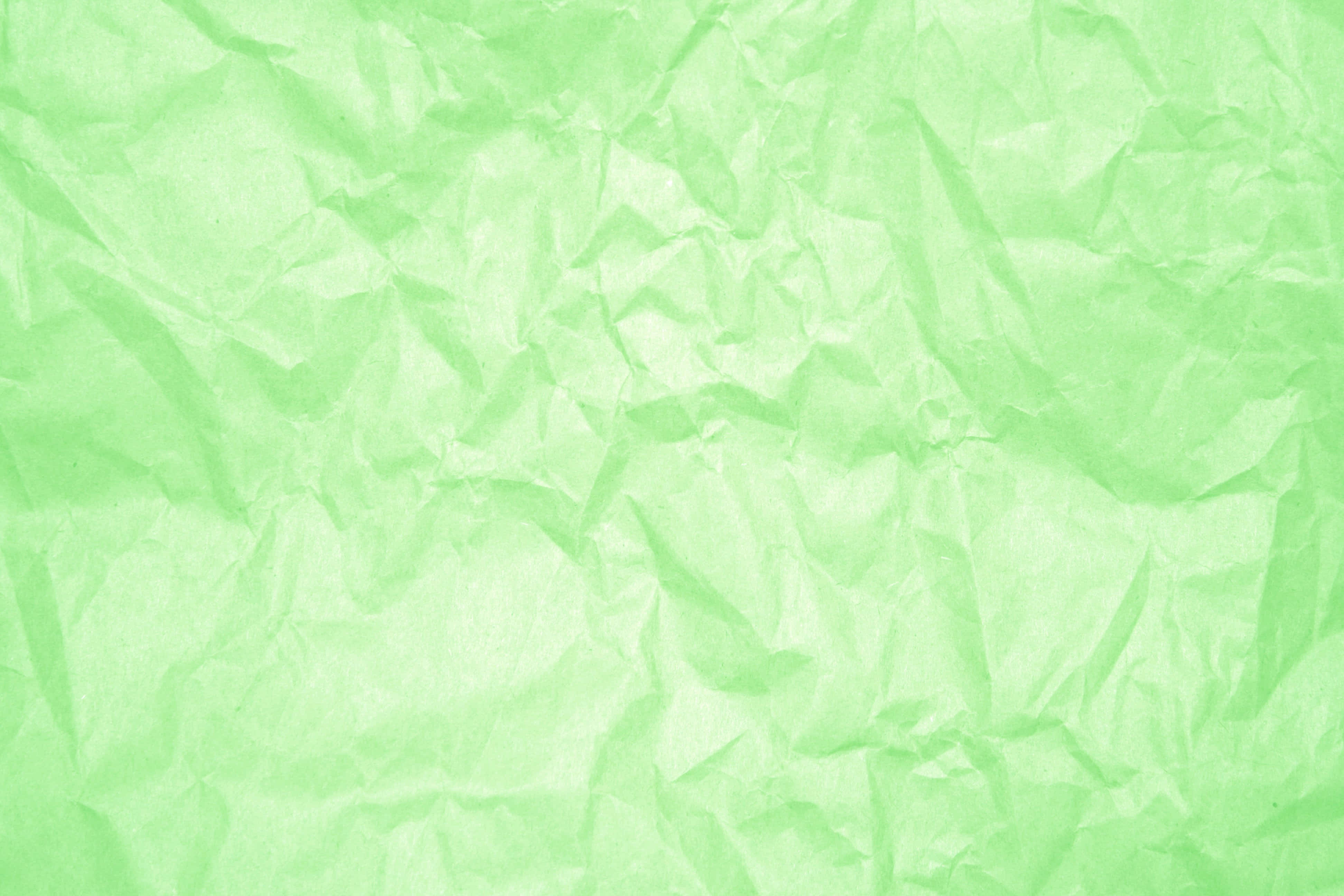 Green Texture 桌布 壁紙 — 淺綠色皺紙的特寫，柔和陰影突出其紋理摺痕。