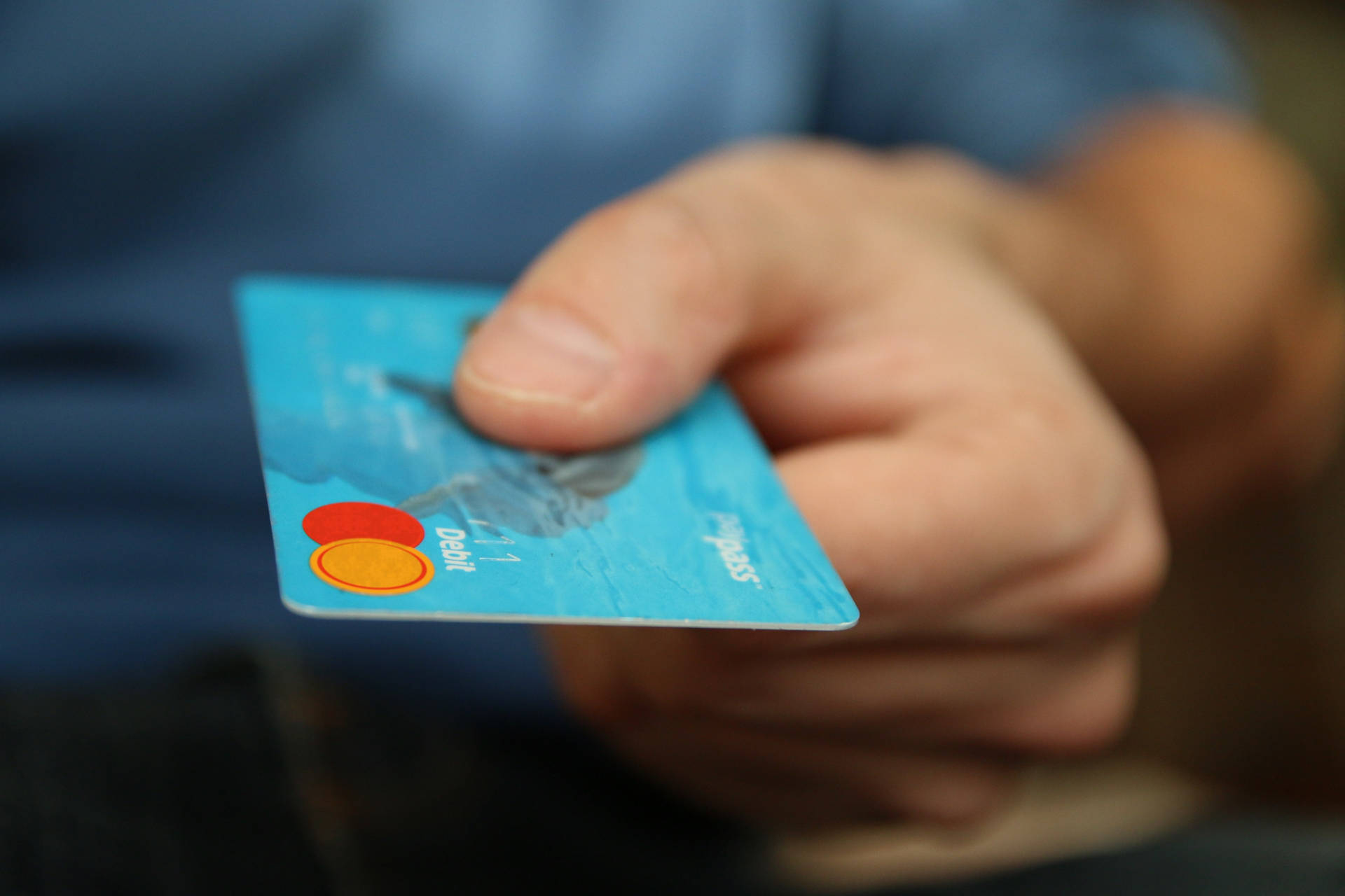 手拿著藍色Mastercard扣賬卡進行付款。