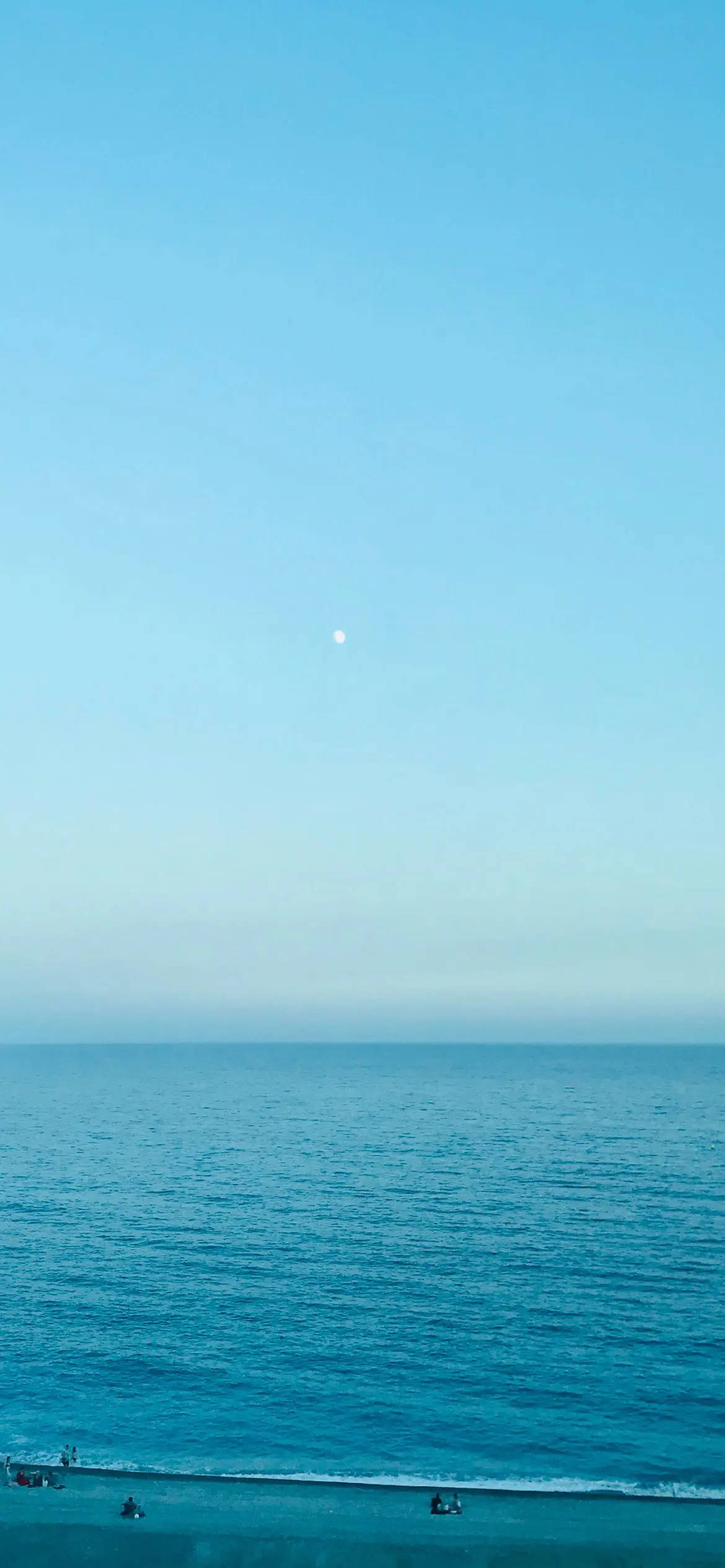 平靜的海洋與晴朗的天空相遇，月亮在上方
