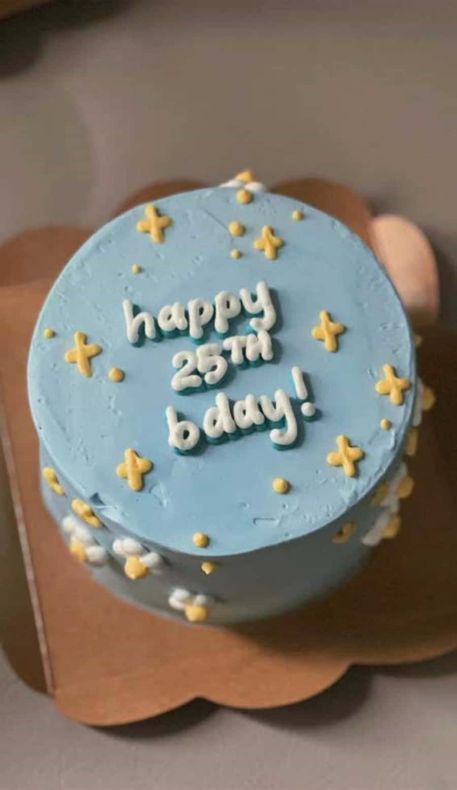 生日蛋糕 桌布 壁紙 — 淺藍色糖霜生日蛋糕，白色糖霜寫著 happy 25th bday，周圍有黃色星星和圓點裝飾。