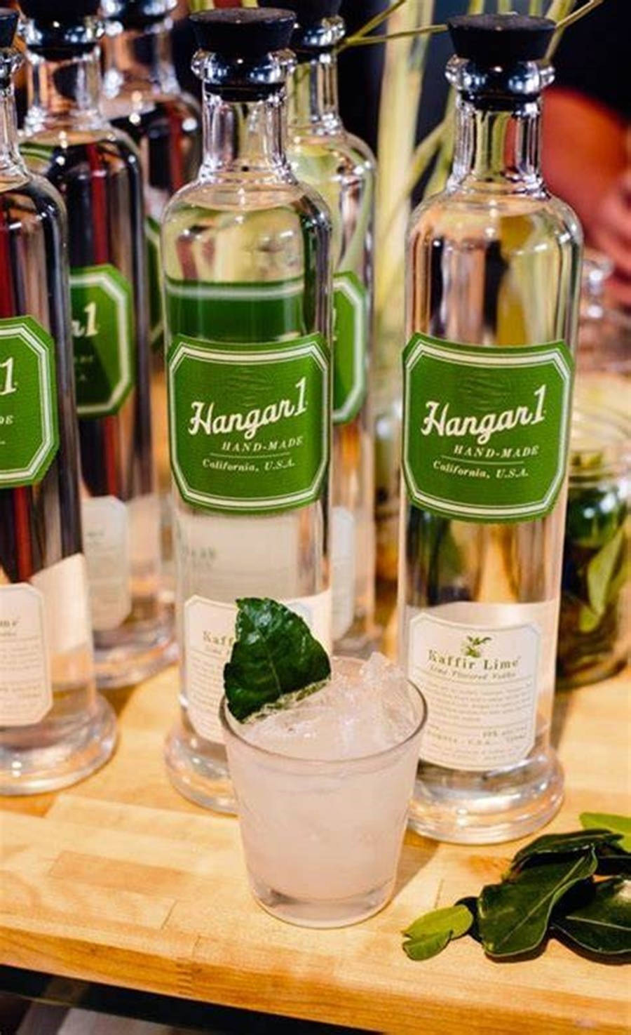 清新 Hangar 1 伏特加配青檸 壁紙 — Hangar 1 手工氈酒瓶和青檸雞尾酒在木製托盤上的特寫。