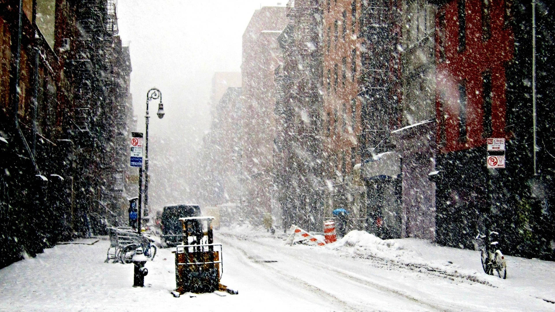 暴風雪中，一條被雪覆蓋的城市街道，有磚砌建築和停放的自行車。