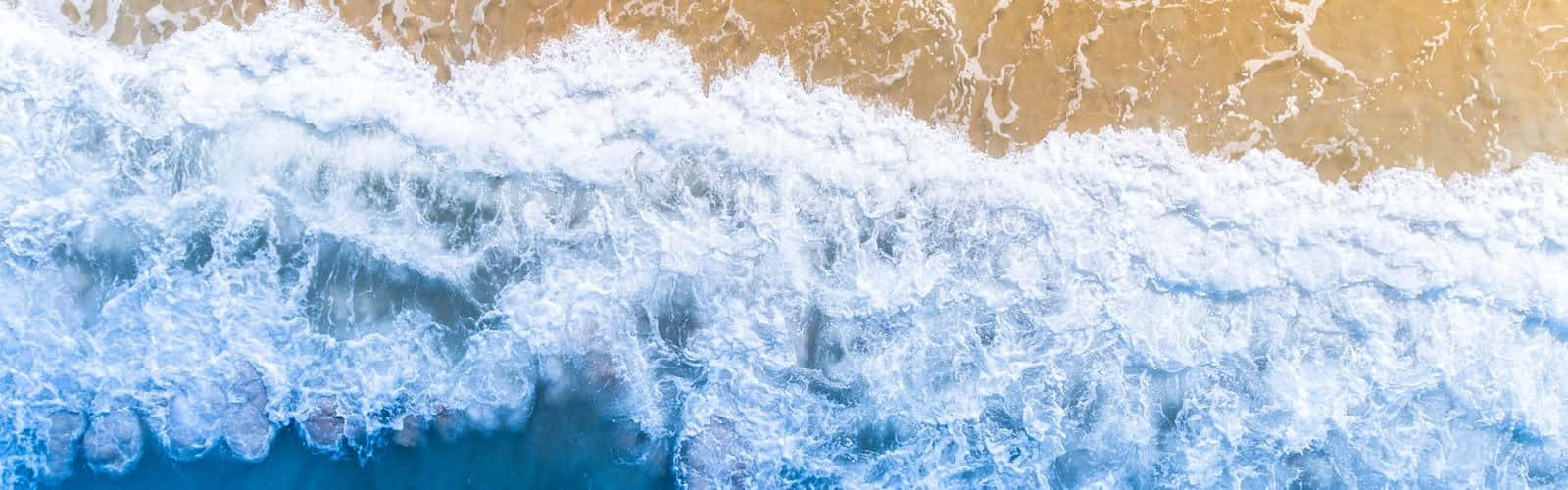 從上方看到的碧綠海水和金色沙灘上拍打的海浪。