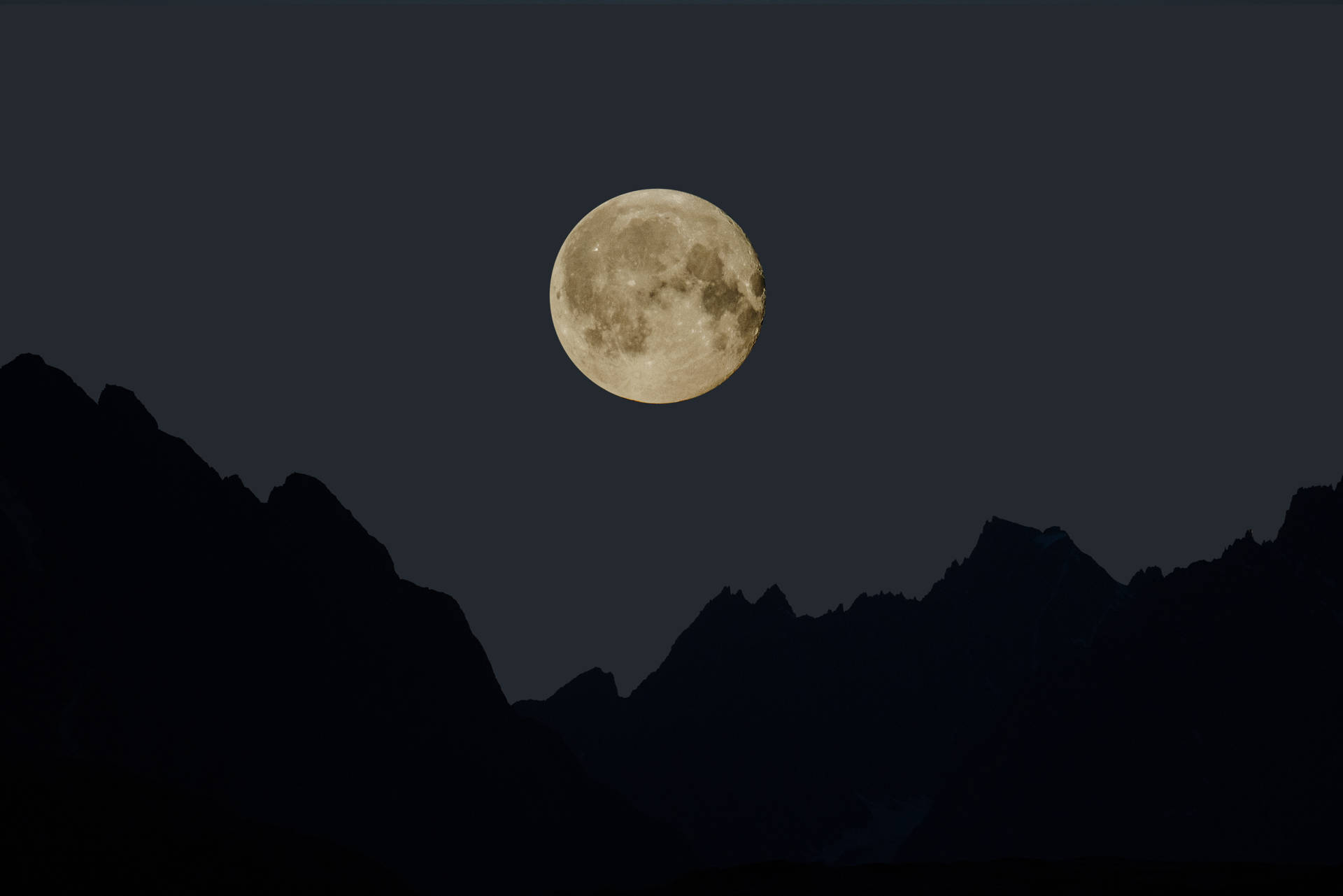 滿月在夜間從黑暗的山峰上升起。