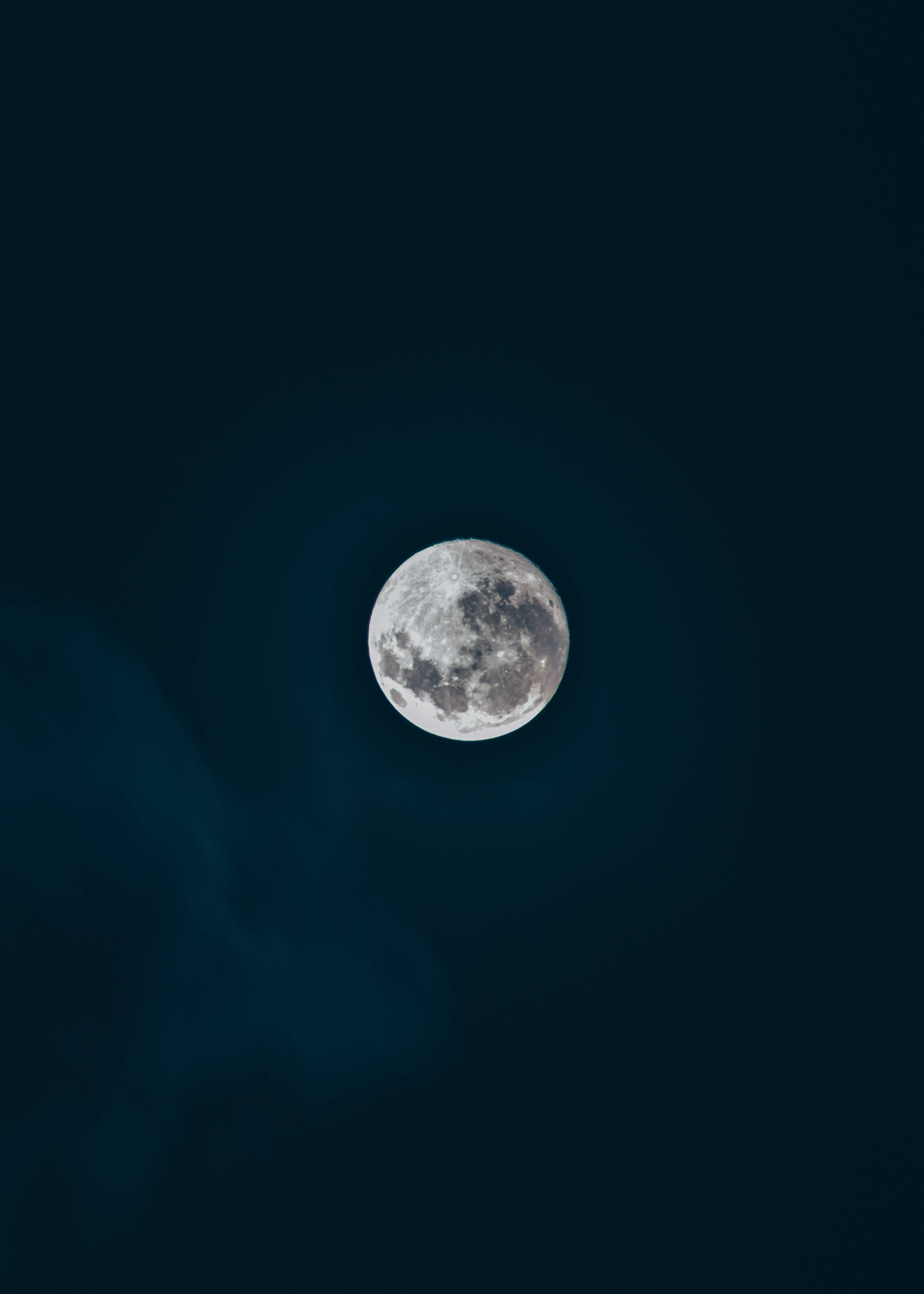 清澈夜空中的美麗滿月 壁紙 — 一輪滿月柔和地發光，映襯著深靛藍色的夜空，薄雲飄過。