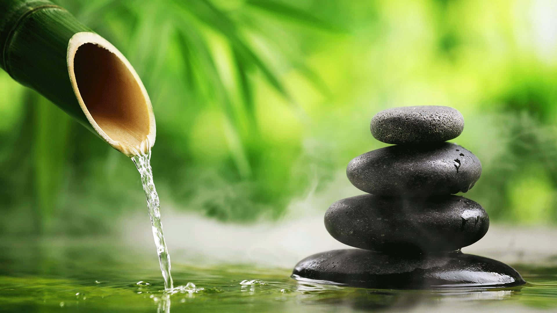 Relaxing Desktop 桌布 壁紙 — 清澈的水從竹管流入池塘，旁邊是一堆光滑的黑石，周圍有霧氣升騰。
