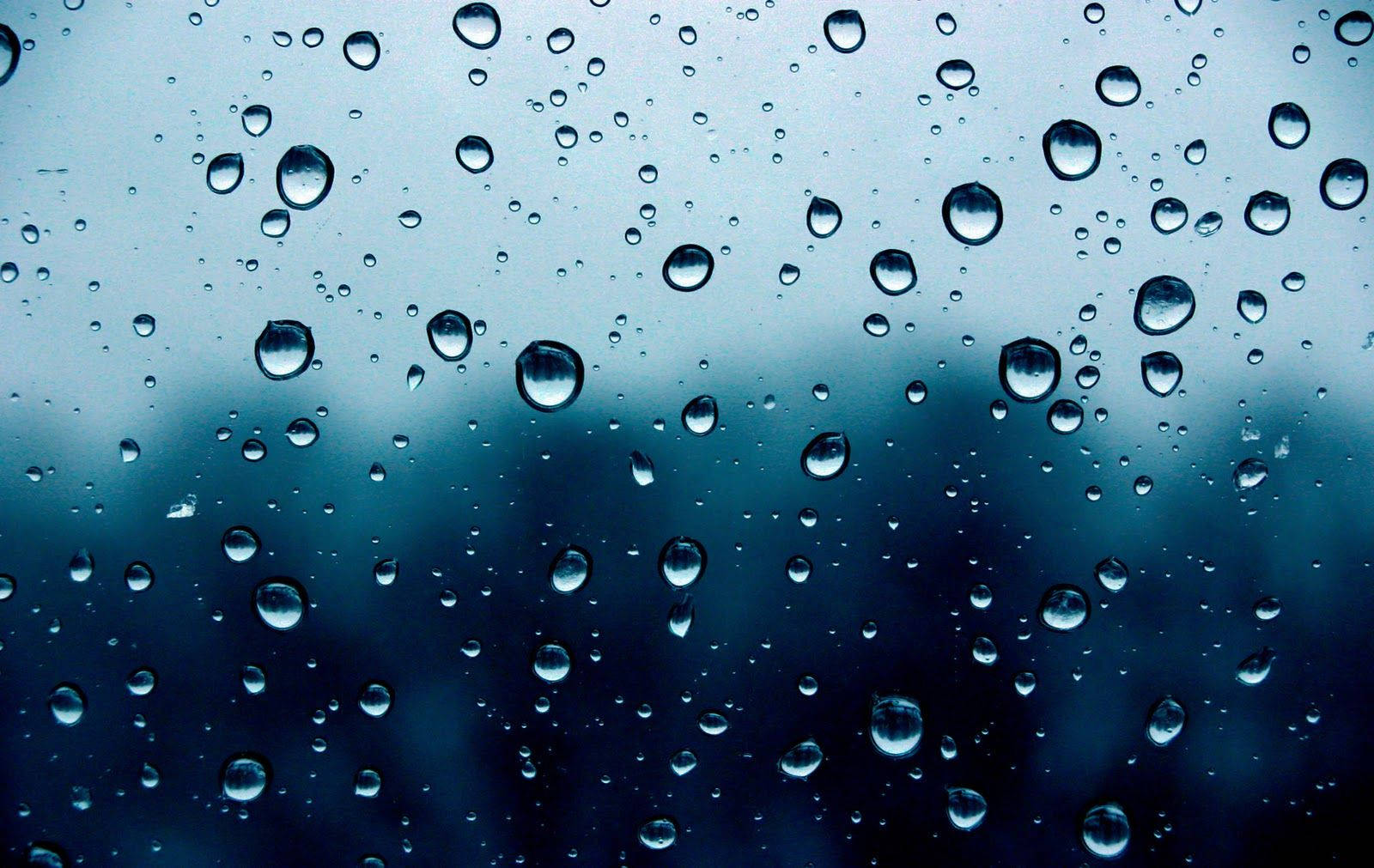 玻璃上的雨滴，背景模糊藍灰色