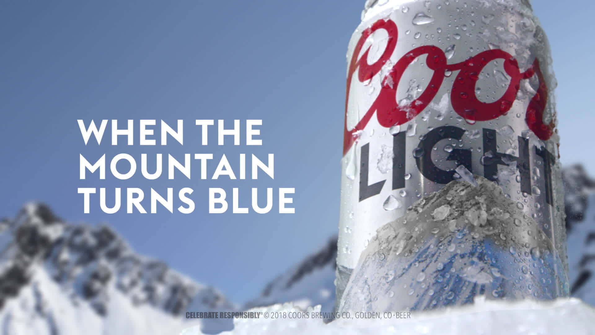 雪地中的Coors Light啤酒罐，以山脈和藍天為背景。
