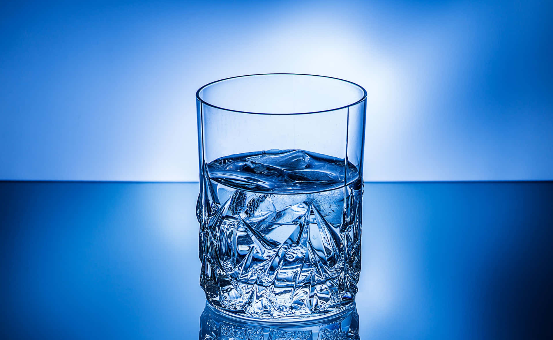 水晶杯裝冰水在藍色反射表面