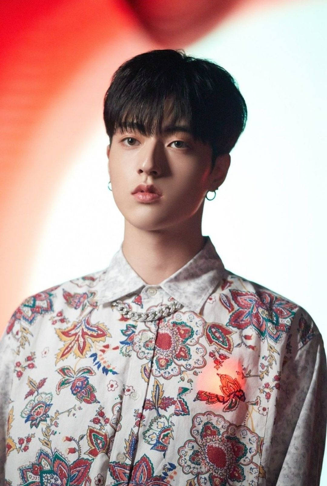 渡邊一馬《I Love You》MV 壁紙 — 一位深色頭髮、戴著圓環耳環的年輕男子，穿著色彩繽紛的花襯衫，背景是柔和的紅白漸變色。