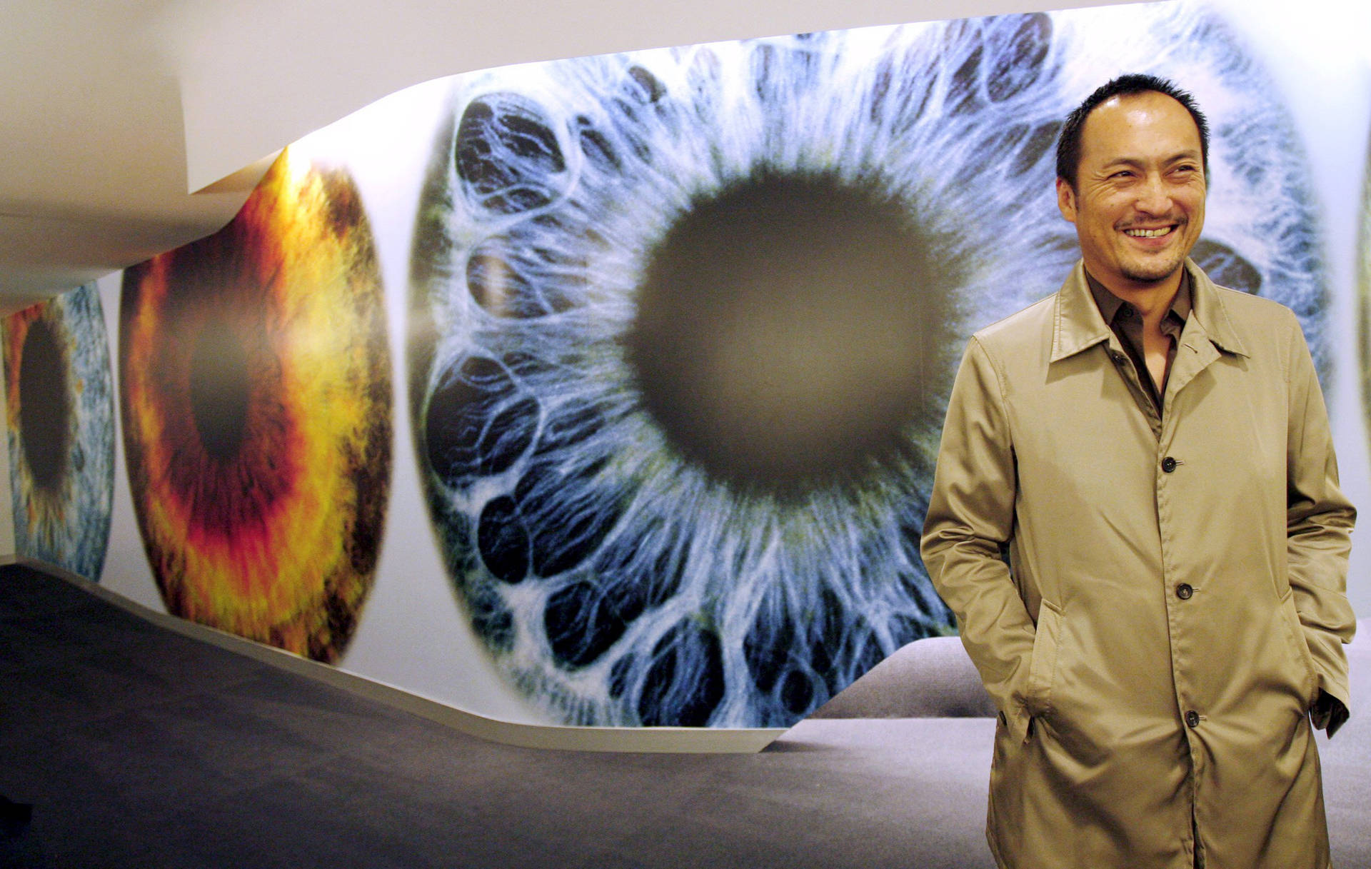身穿米色外套的男子在眼睛解剖牆展示前微笑。