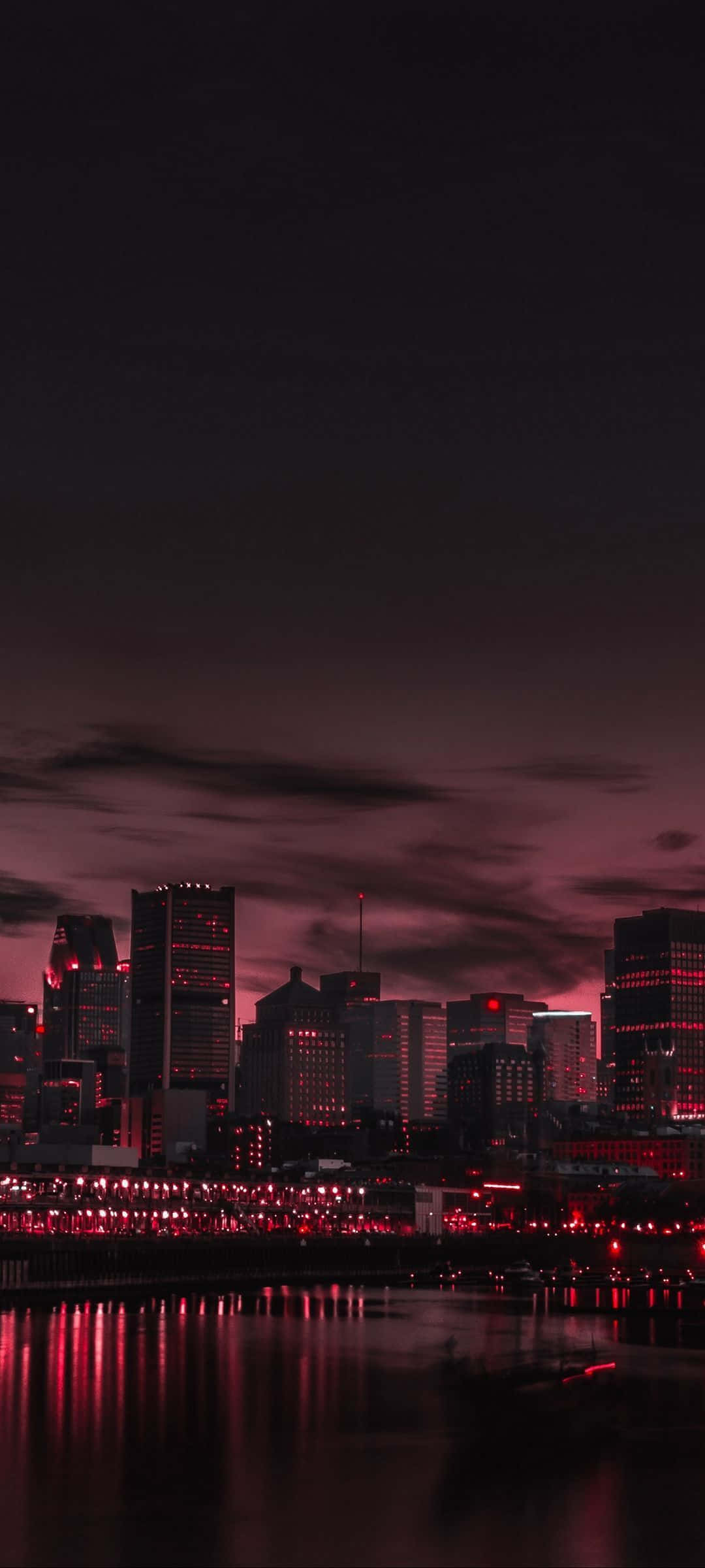 港灣摩天樓夜景 壁紙 — 黃昏時分的城市天際線沐浴在深紅色的光芒中，倒影在水面上閃爍。