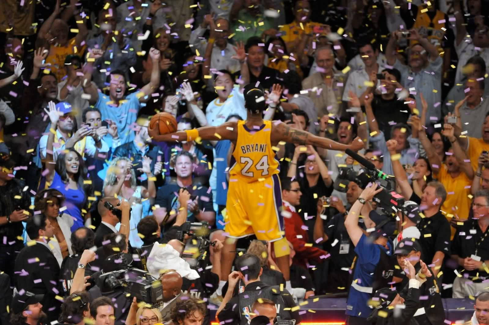 身穿黃色球衣的籃球運動員在五彩紙屑中與歡呼的球迷慶祝勝利。