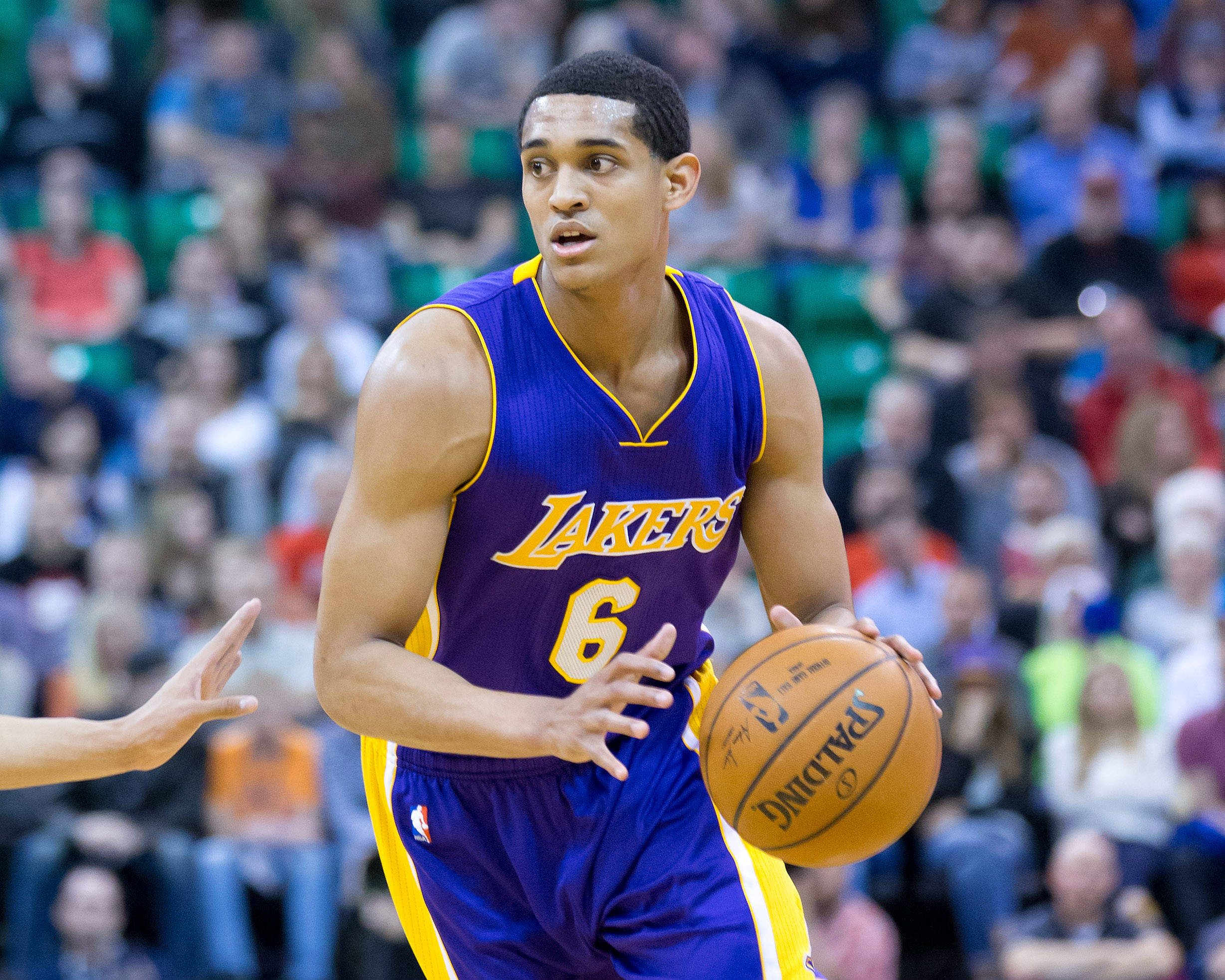 湖人隊球員Jordan Clarkson 壁紙 — 一名身穿紫金色湖人球衣的籃球運動員在激烈的比賽中運球，背景是模糊的人群。
