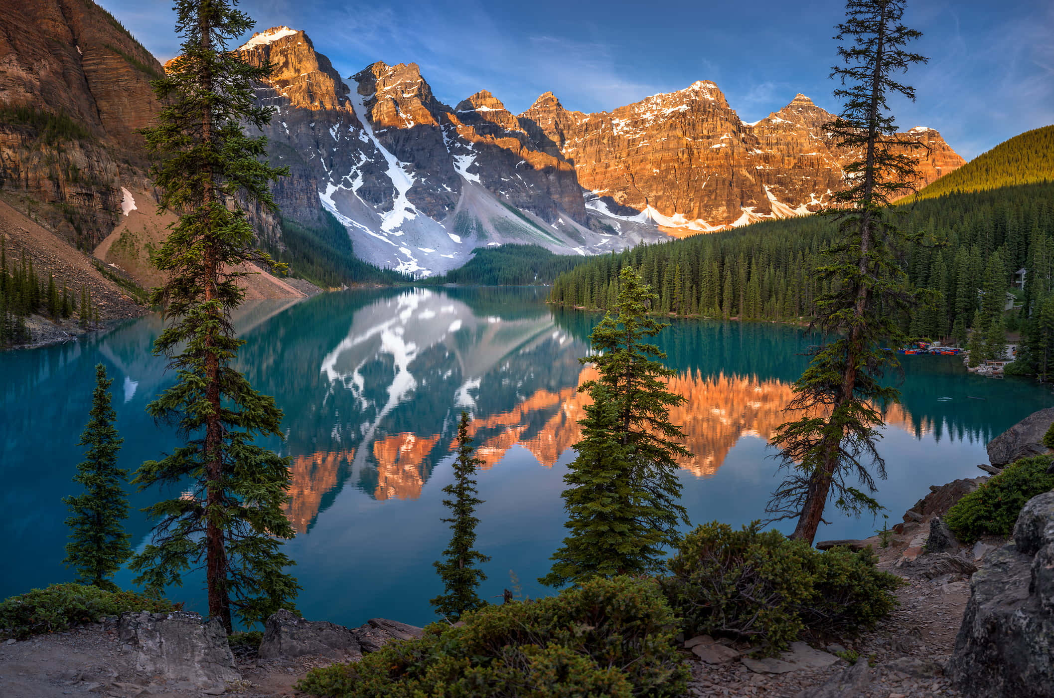 湖光山色的高品質自然風景 壁紙 — 一個令人驚嘆的山湖，在晴朗的藍天下，映照著白雪覆蓋的山峰和金色的懸崖，四周環繞著高大的松樹。