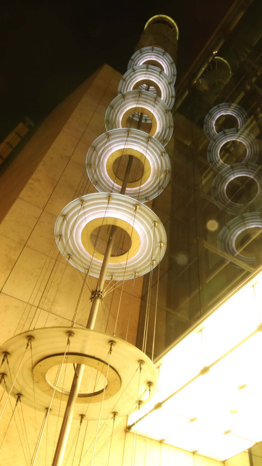 夜間懸掛在現代建築前的發光圓形光雕塑。