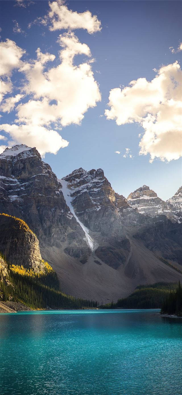 湖光山色風景畫 壁紙 — 一個令人驚嘆的山湖，湖水呈碧綠色，倒映著白雪覆蓋的山峰，在明亮的藍天下有蓬鬆的白雲。