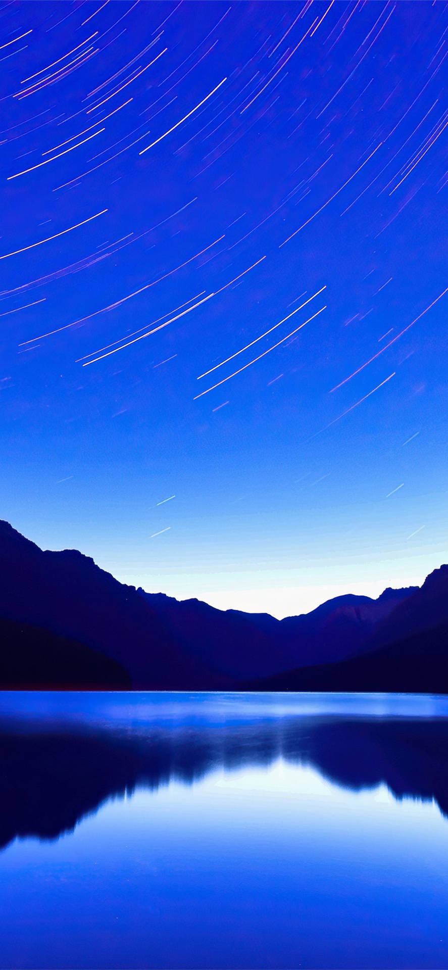 在深藍色夜空下，寧靜的山湖中倒映的星軌。
