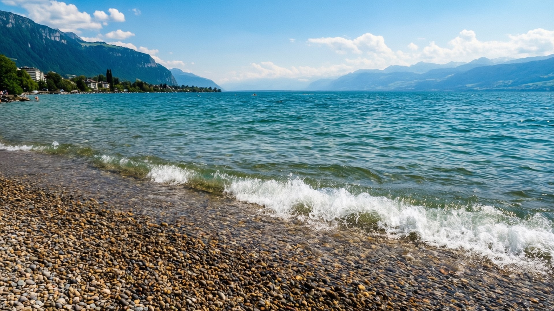 海浪湧上卵石海灘，背景有山和藍天。