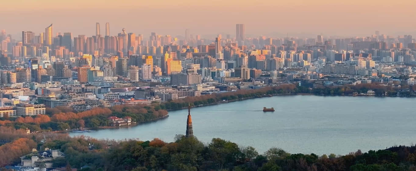 日落時分的城市天際線，前景有湖和船，周圍環繞著樹木。 — 旅行 壁紙