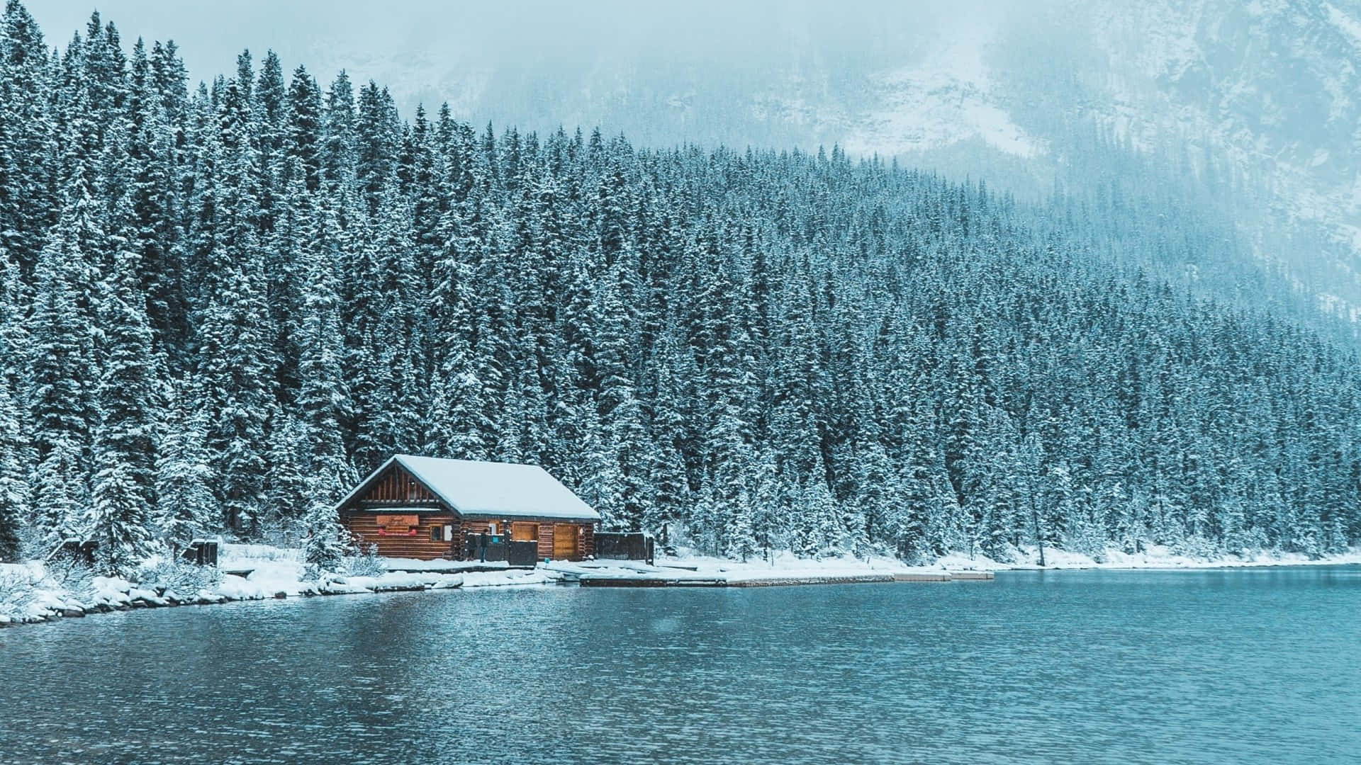 白雪覆蓋的小屋，位於寧靜的湖邊，被松樹和山巒環繞。