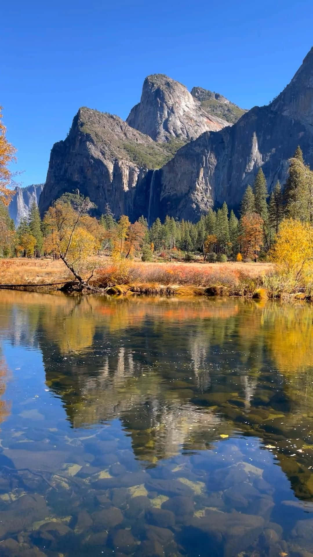 湖畔風景 壁紙 — 清澈的河流映照著高聳的花崗岩懸崖和秋樹，天空湛藍。
